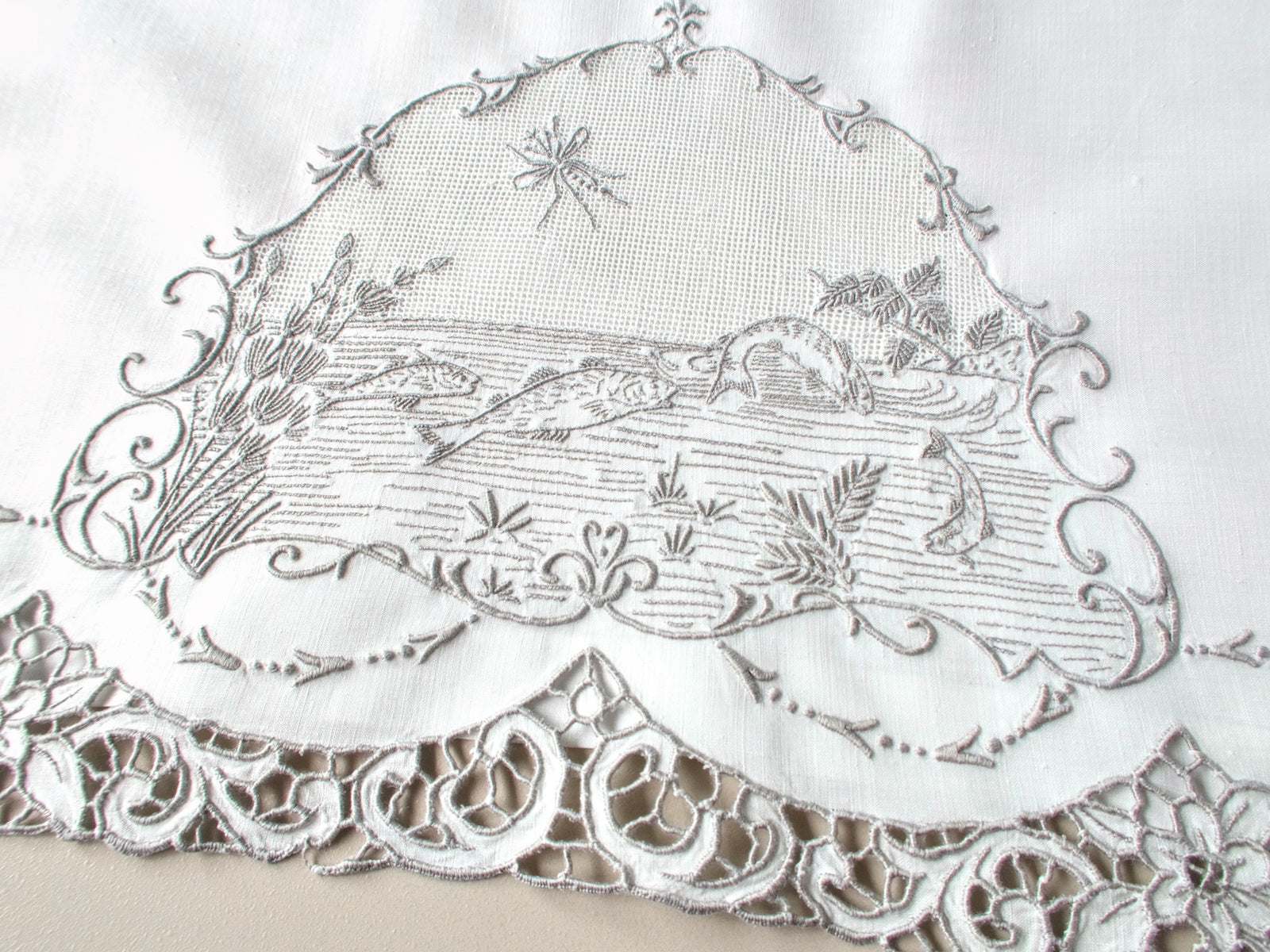 Antique Italian hand embroidered guest towel, fish swimming among reeds and water plants beneath open mesh sky with dragonfly, scrolling floral border.