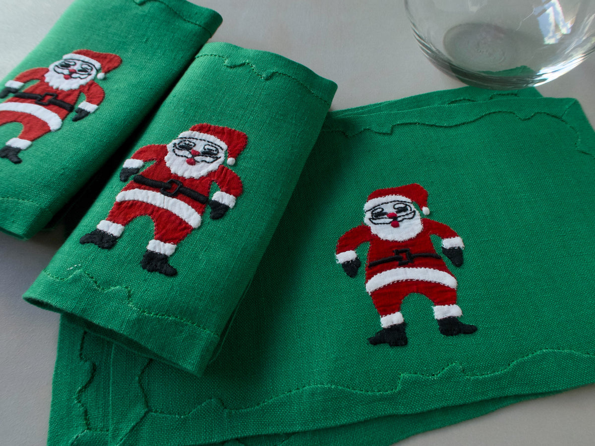 Green linen cocktail napkins with  hand-embroidered Santas in red suits,  handmade in Madeira