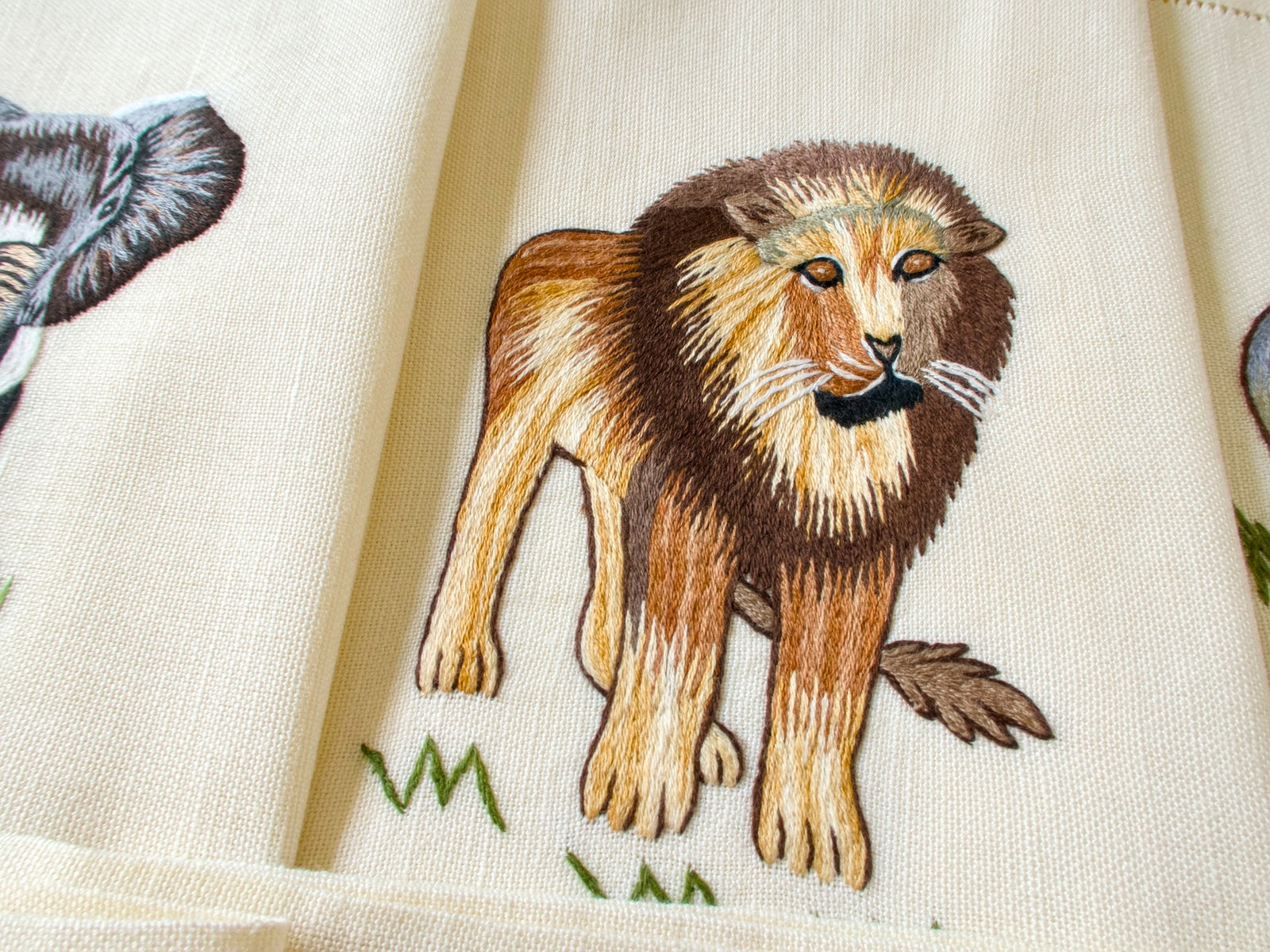 Close-up of vintage hand embroidered placemat showing lion with full mane, detailed naturalistic embroidery on linen