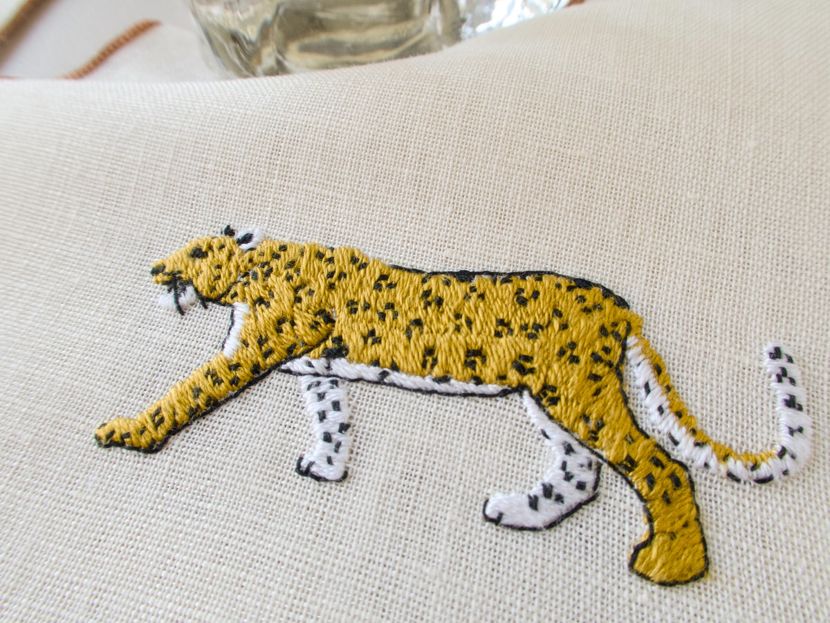 Close-up of vintage cocktail napkin, detailed embroidered cheetah in golden tones on semi-sheer ecru linen