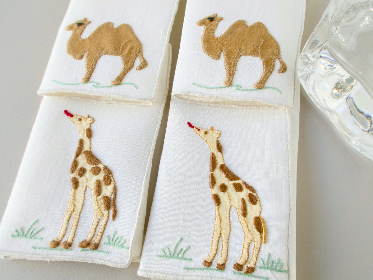 Close-up of vintage Madeira cocktail napkins showing camel and standing giraffe appliqué detail