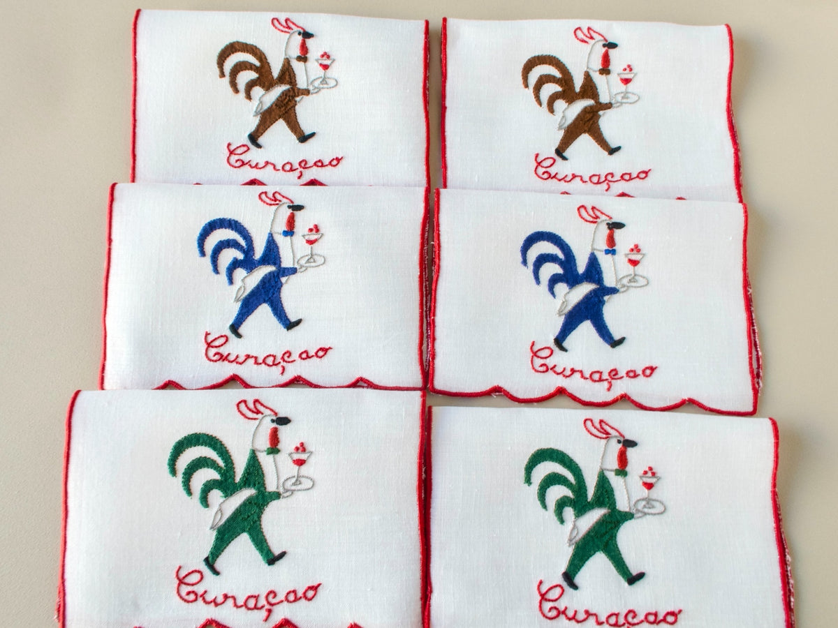 Folded set of vintage Madeira hand embroidered rooster cocktail napkins, white linen with red trim.