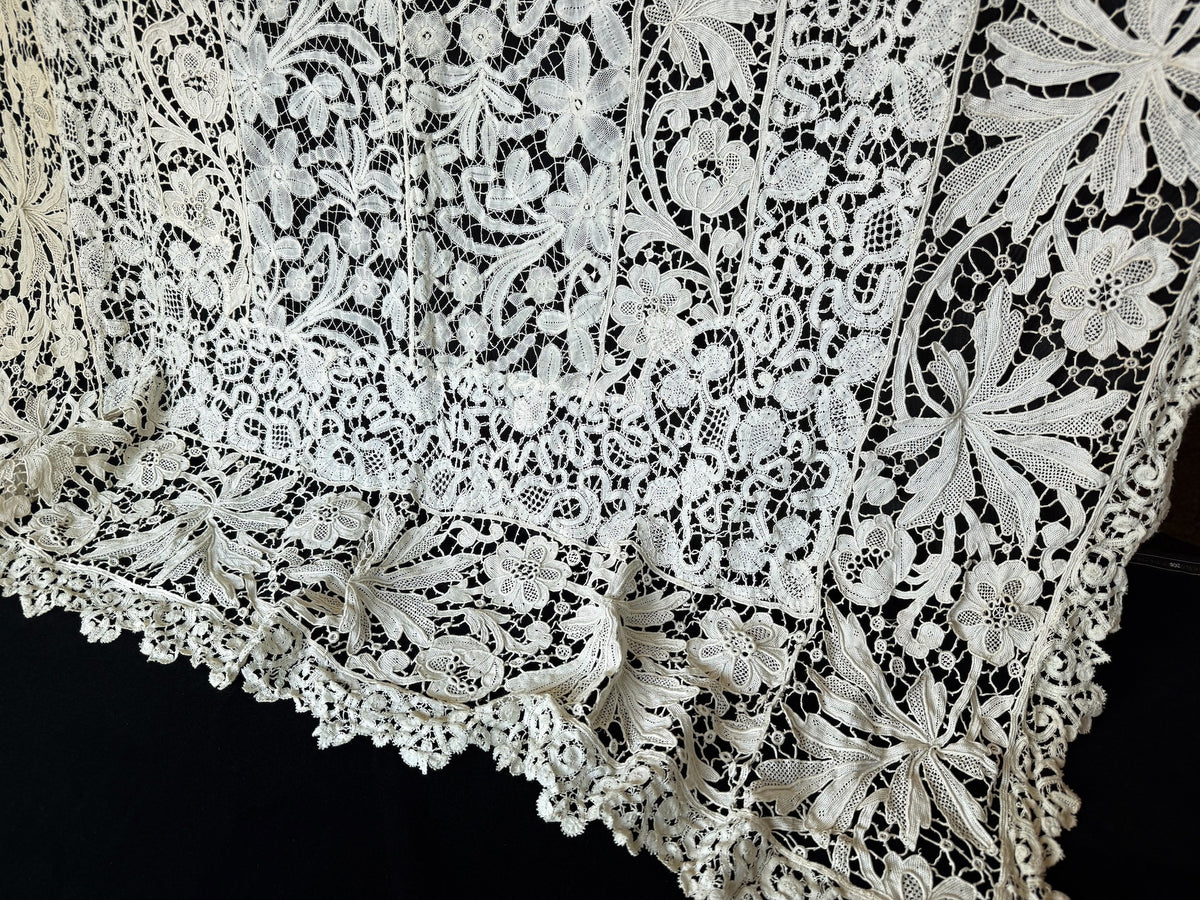 Opposite end of the antique French lace tablecloth with scrolling bobbin lace panels and a scalloped border, no cranes