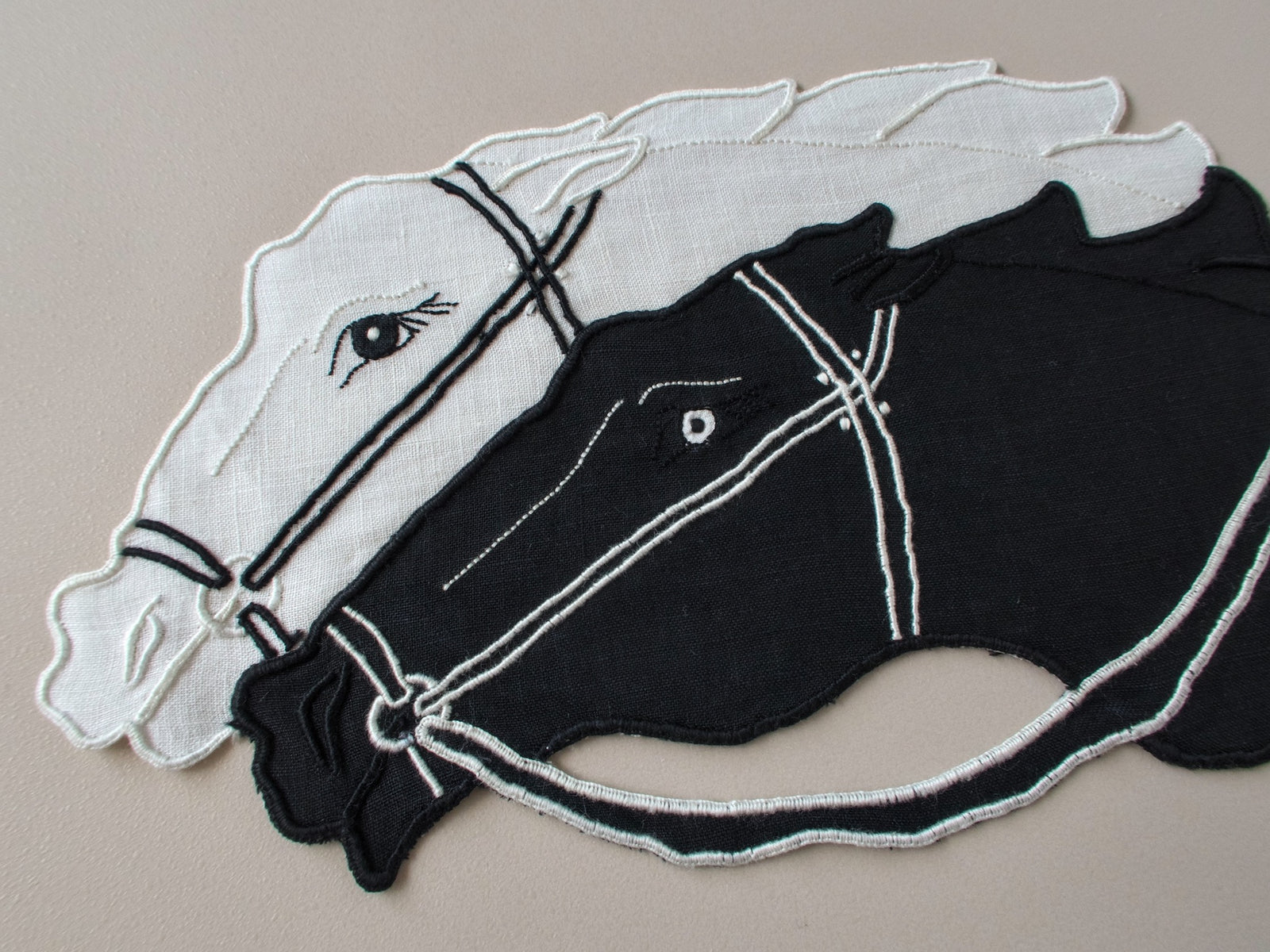 Close-up detail of vintage Madeira hand embroidered cocktail napkin, black and white racing horses, appliqué and embroidery work