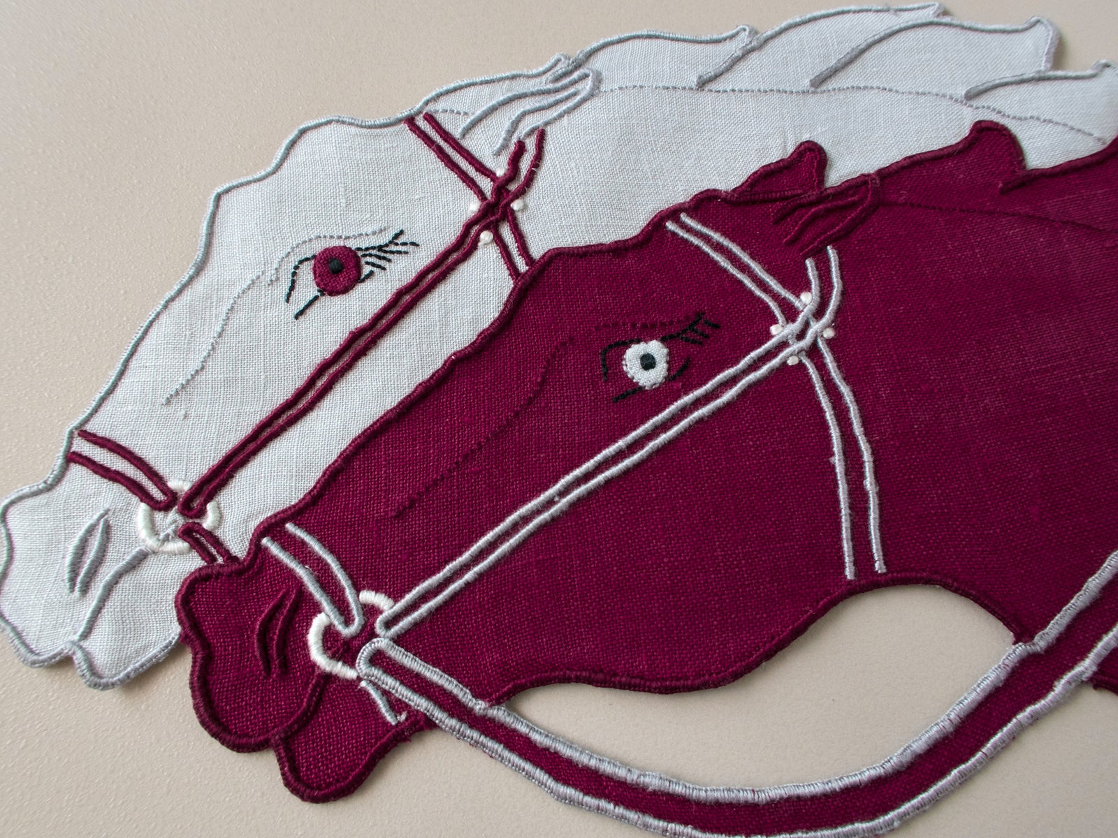 Close-up detail of vintage Madeira hand embroidered cocktail napkin, burgundy and gray racing horses, appliqué and embroidery work