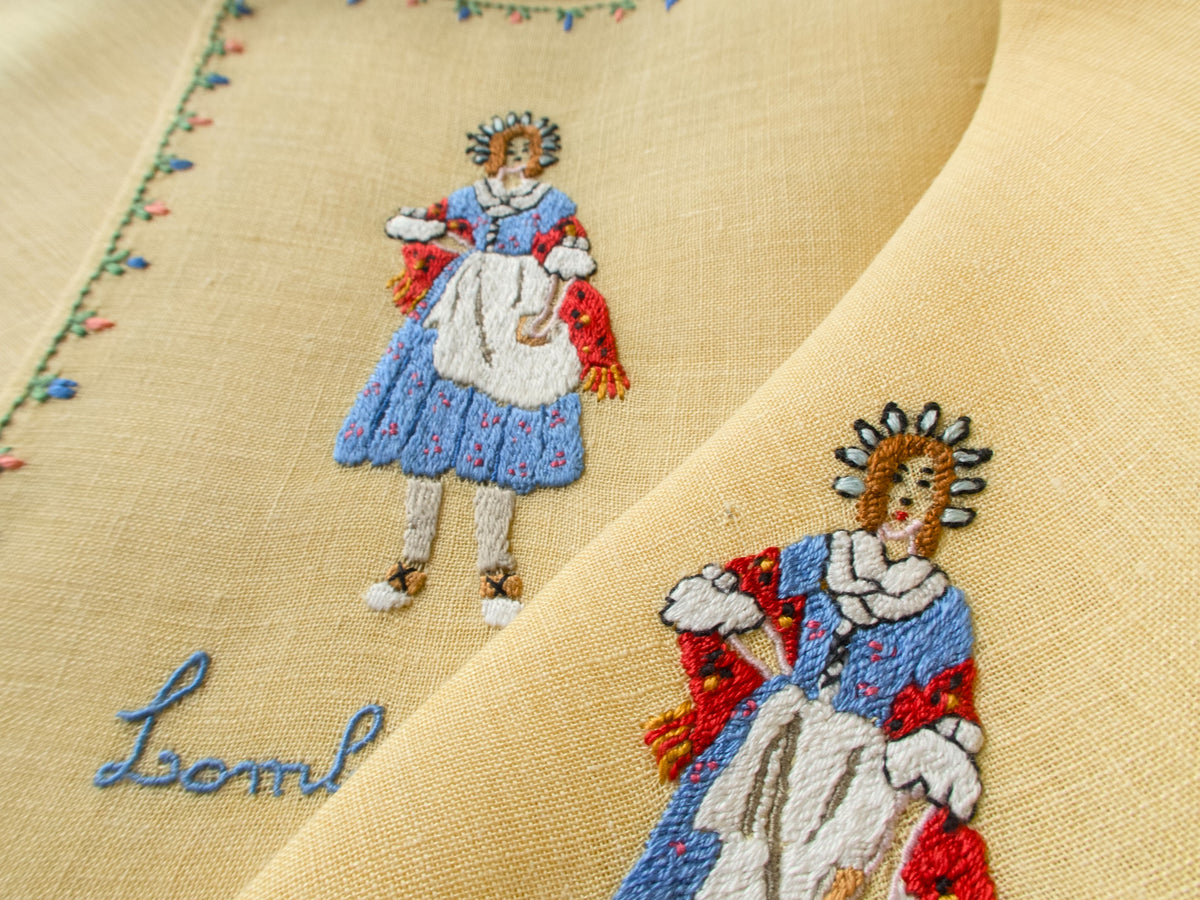 Detailed embroidery of Rapisardi costumed figure on yellow linen placemat