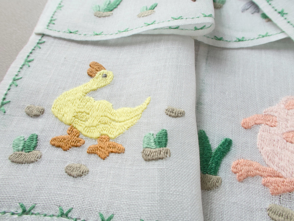 Close-up of Rapisardi  duck embroidery on white linen cocktail napkins.