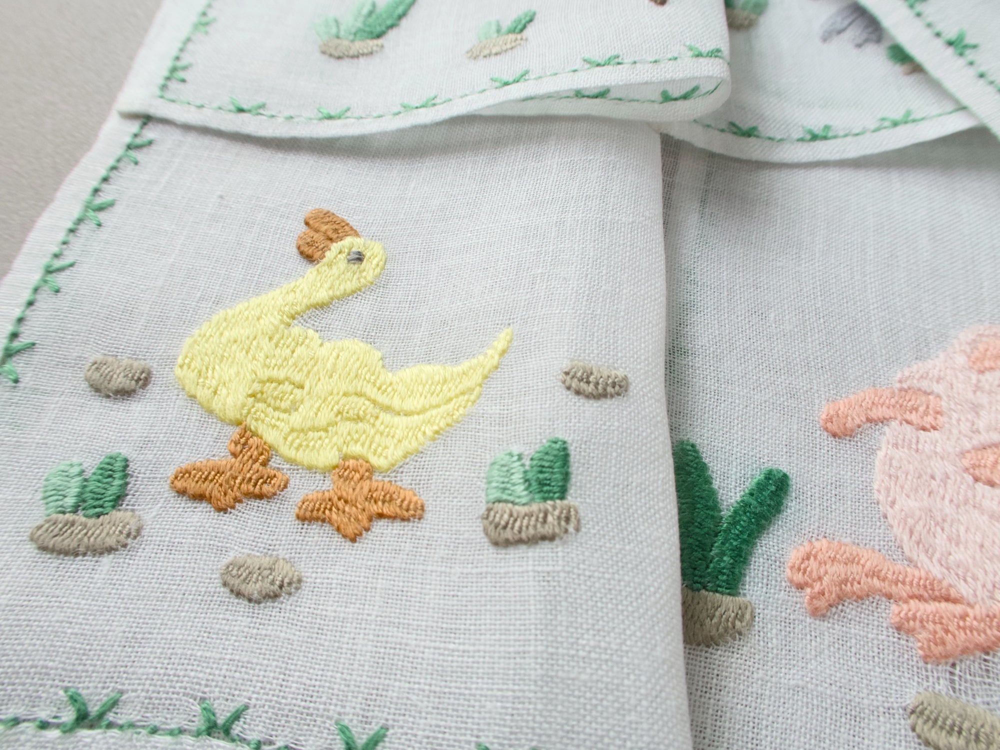Close-up of Rapisardi  duck embroidery on white linen cocktail napkins.