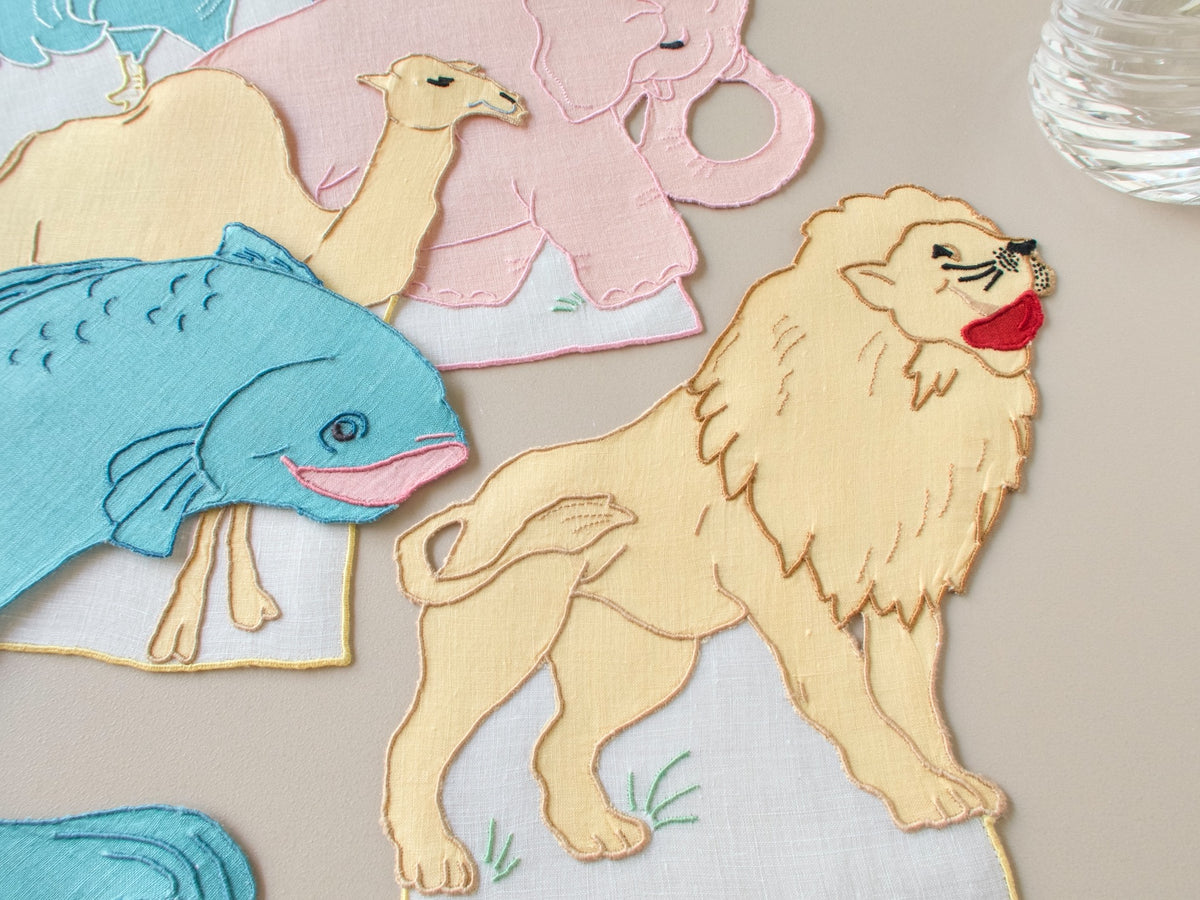 Detail of vintage Madeira hand embroidered lion cocktail napkin with teal fish, golden linen, gently used​​​​​​​​​​​​​​​​