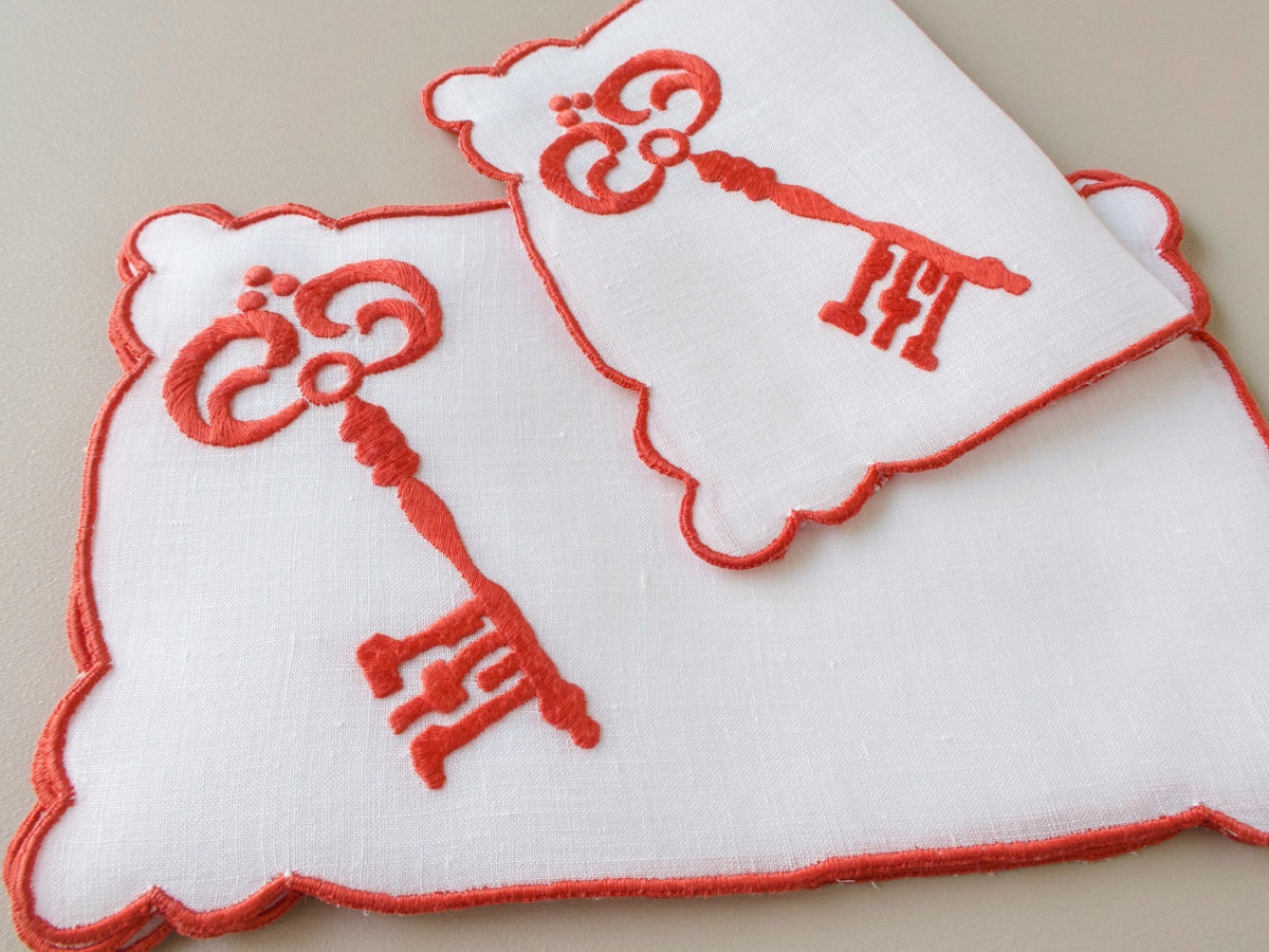 Stacked vintage white linen Madeira cocktail napkins, hand embroidered red skeleton key motif, scalloped edges, set of 6
