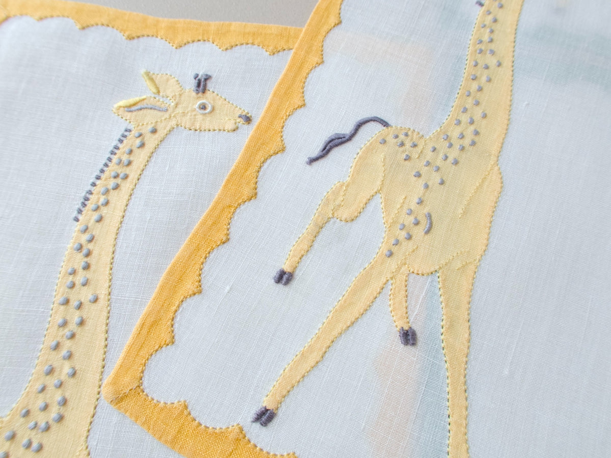 Closeup of vintage Madeira cocktail napkins, appliqué giraffe in profile with yellow repliqué border detail​​​​​​​​​​​​​​​​