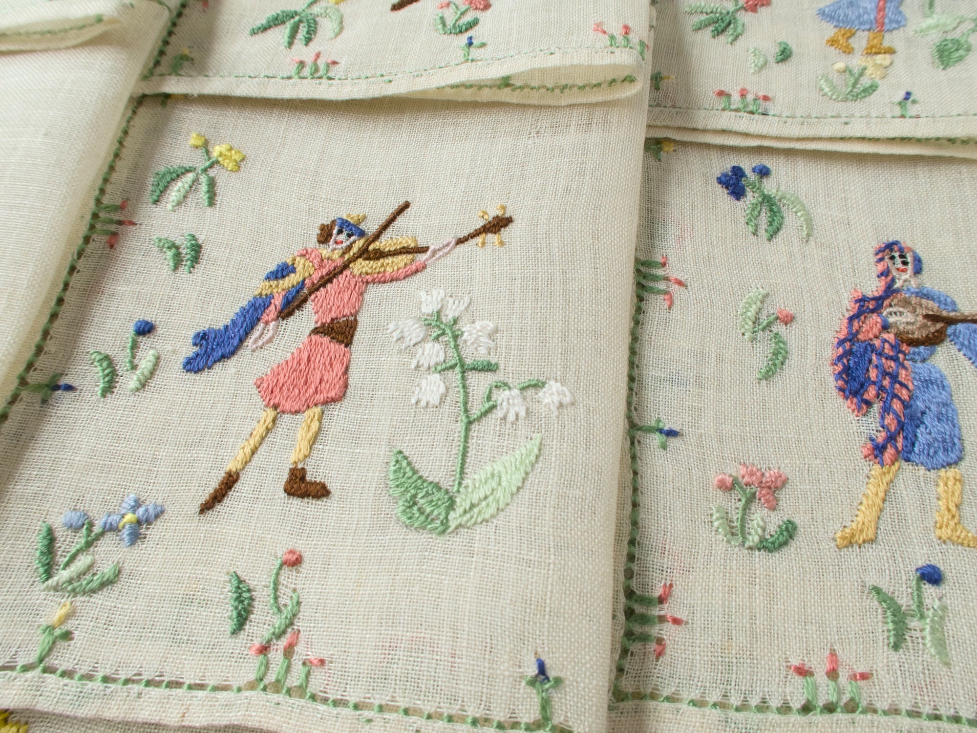 Two musician napkins side by side showing violinist figures and floral motifs.