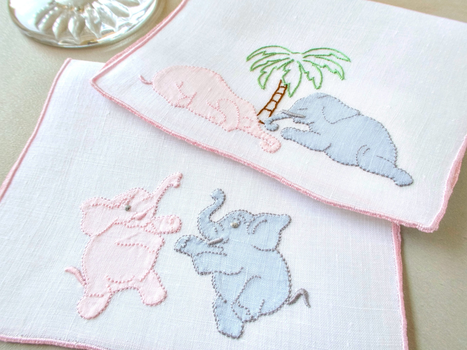 Vintage Madeira cocktail napkins, white linen with pink border, pink and gray appliqué elephants under a palm tree