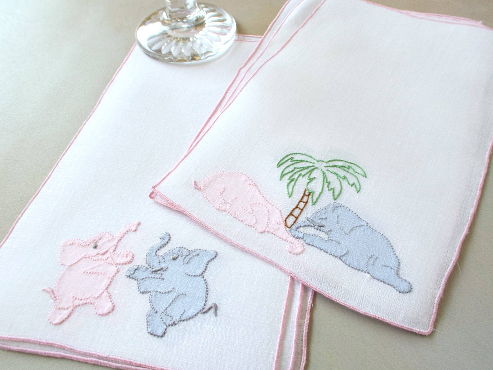 Vintage Madeira cocktail napkins, white linen with pink border, pink and gray appliqué elephants under a palm tree