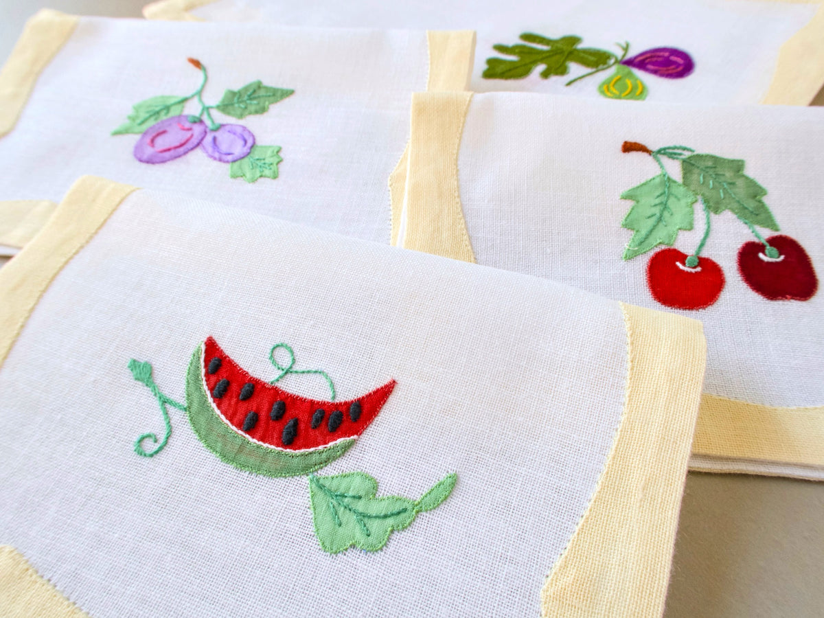 Vintage Italian cocktail napkins showing watermelon slice and cherries hand embroidered on white semi-sheer linen with yellow border