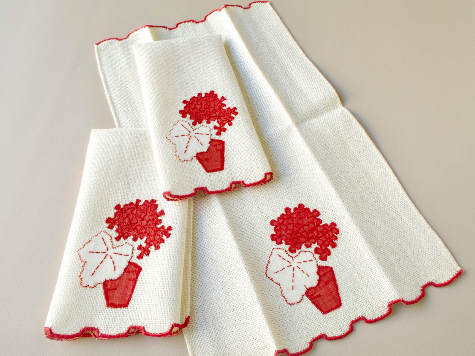 Three vintage Marghab marcasual linen fingertip towels stacked to show the set, with red “Geranium” design and stepped red hem
