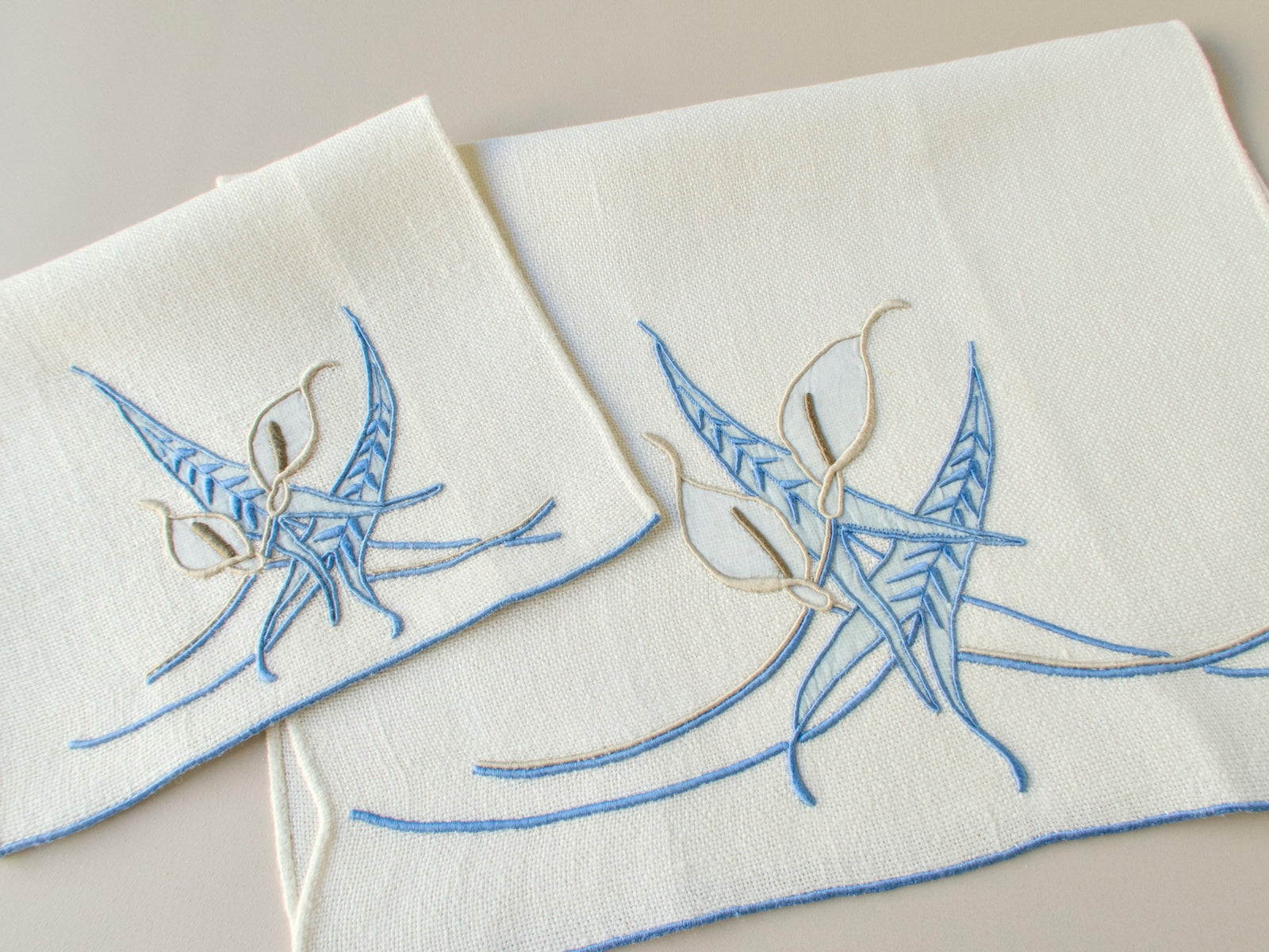 Vintage Marghab marcasual linen hand towel and fingertip towel laid flat showing the full “Calla Lily” embroidery in blue and white​​​​​​​​​​​​​​​​