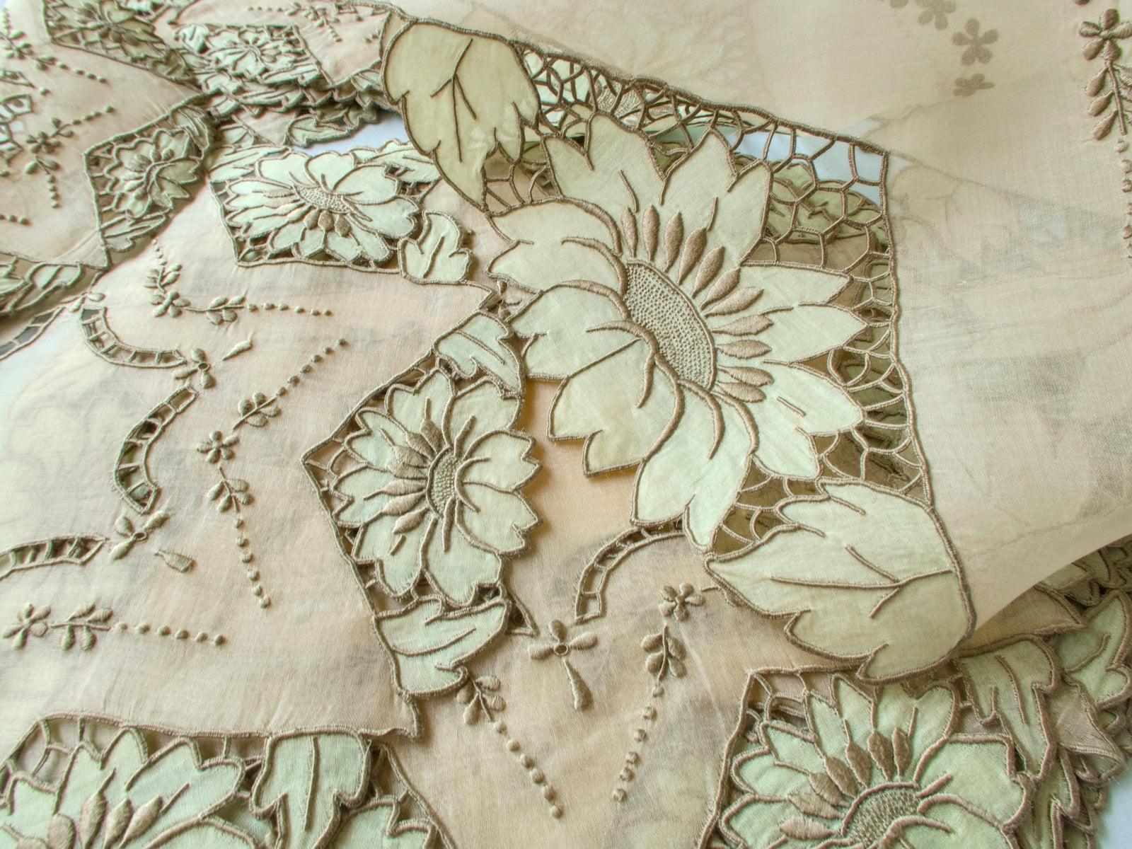 Close-up of sage green sunflower appliqué on vintage Madeira organdy showing embroidery texture and color