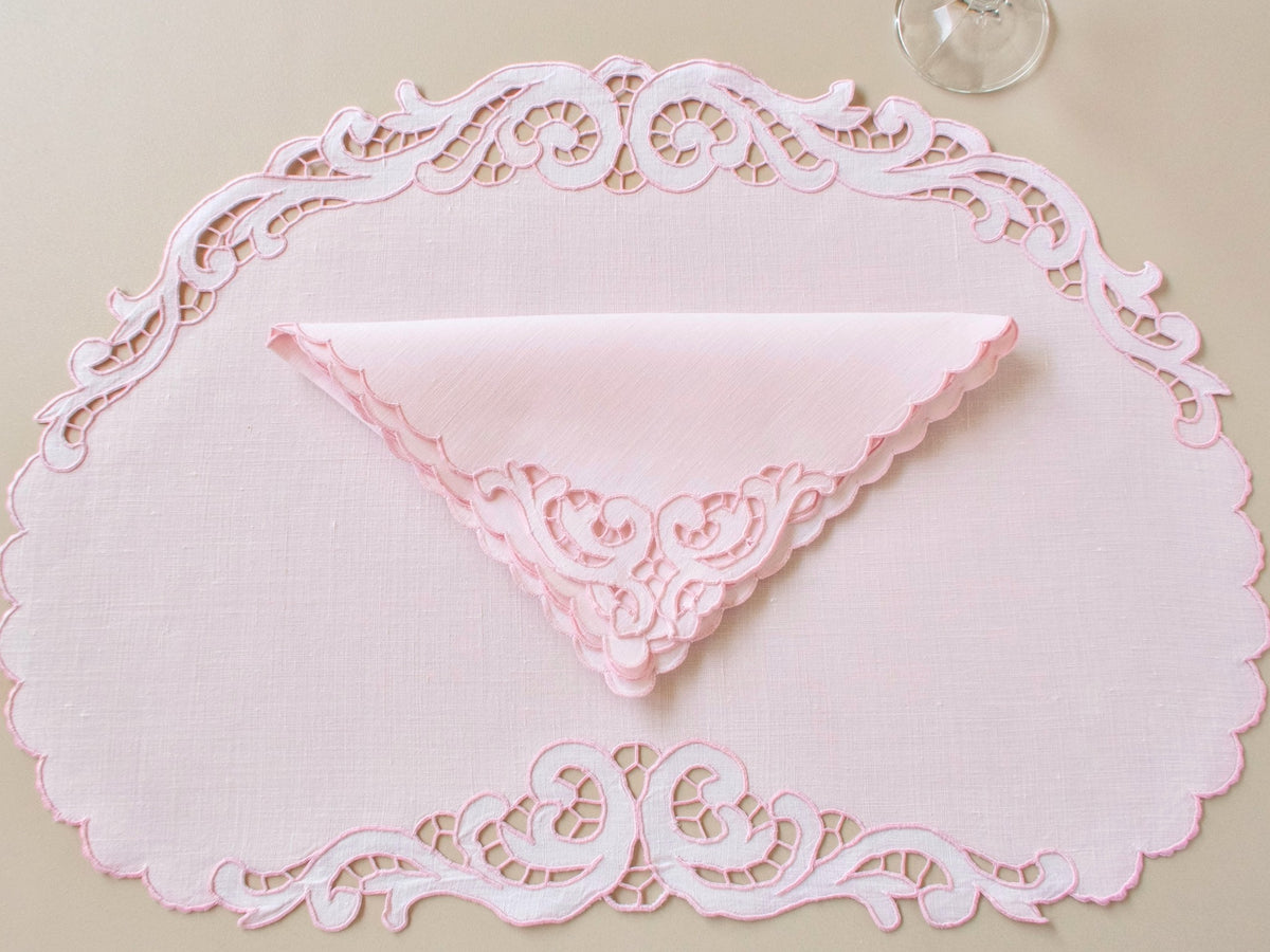 Oval vintage Madeira pink Irish linen placemat with folded napkin showing full scrollwork Richelieu cutwork border