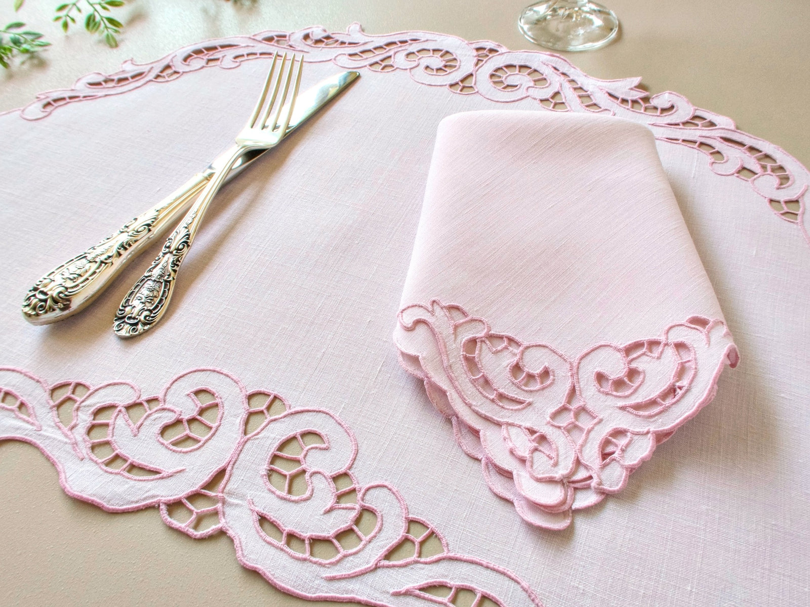 Vintage Madeira pink Irish linen placemat with baroque scrollwork Richelieu cutwork border, silver cutlery and folded napkin styled on table