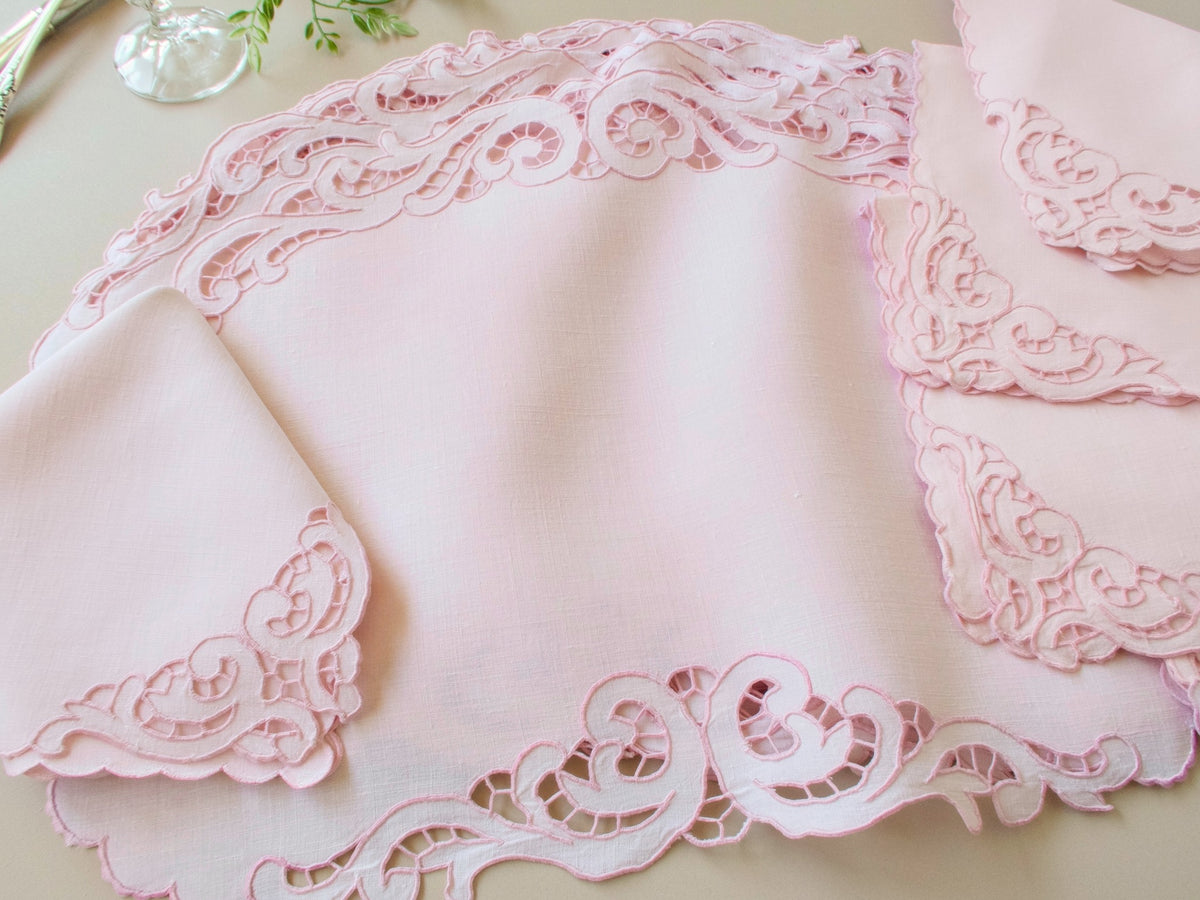 Close-up of vintage Madeira pink Irish linen placemat corner showing baroque scrollwork cutwork and caseado bastido edge detail