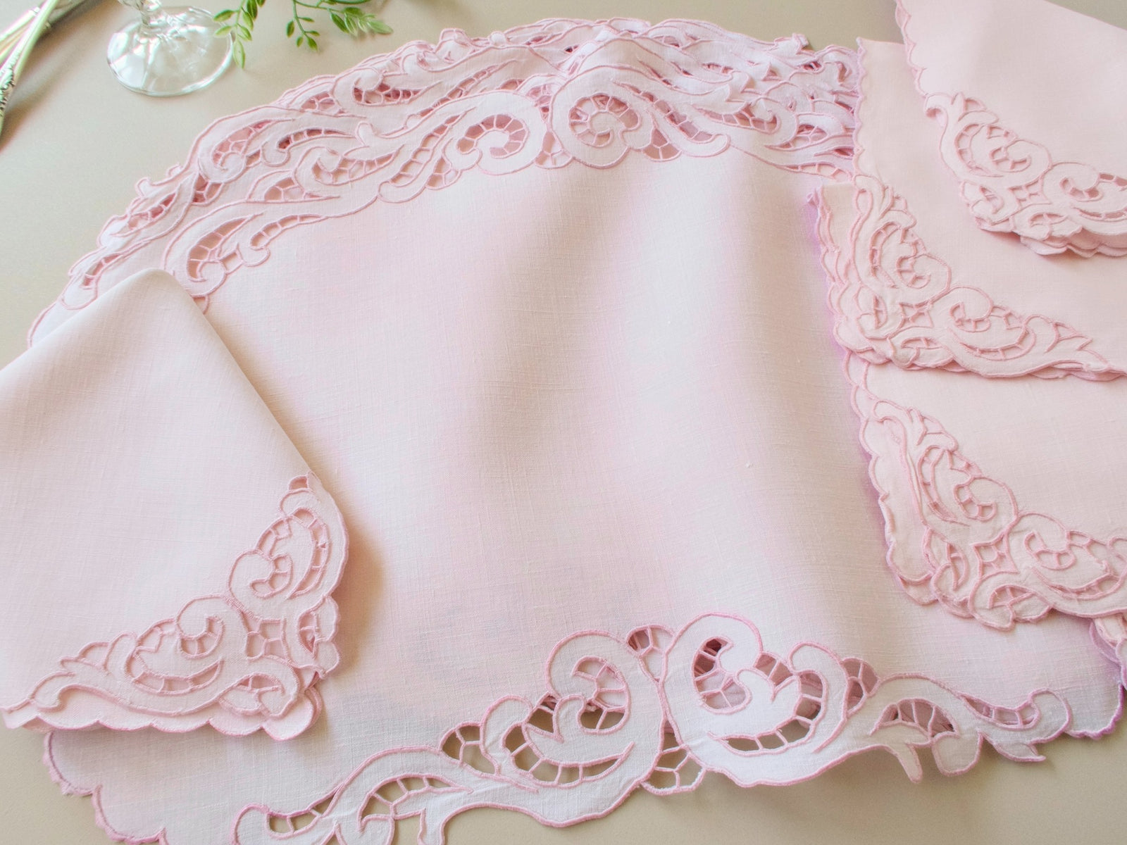 Close-up of vintage Madeira pink Irish linen placemat corner showing baroque scrollwork cutwork and caseado bastido edge detail
