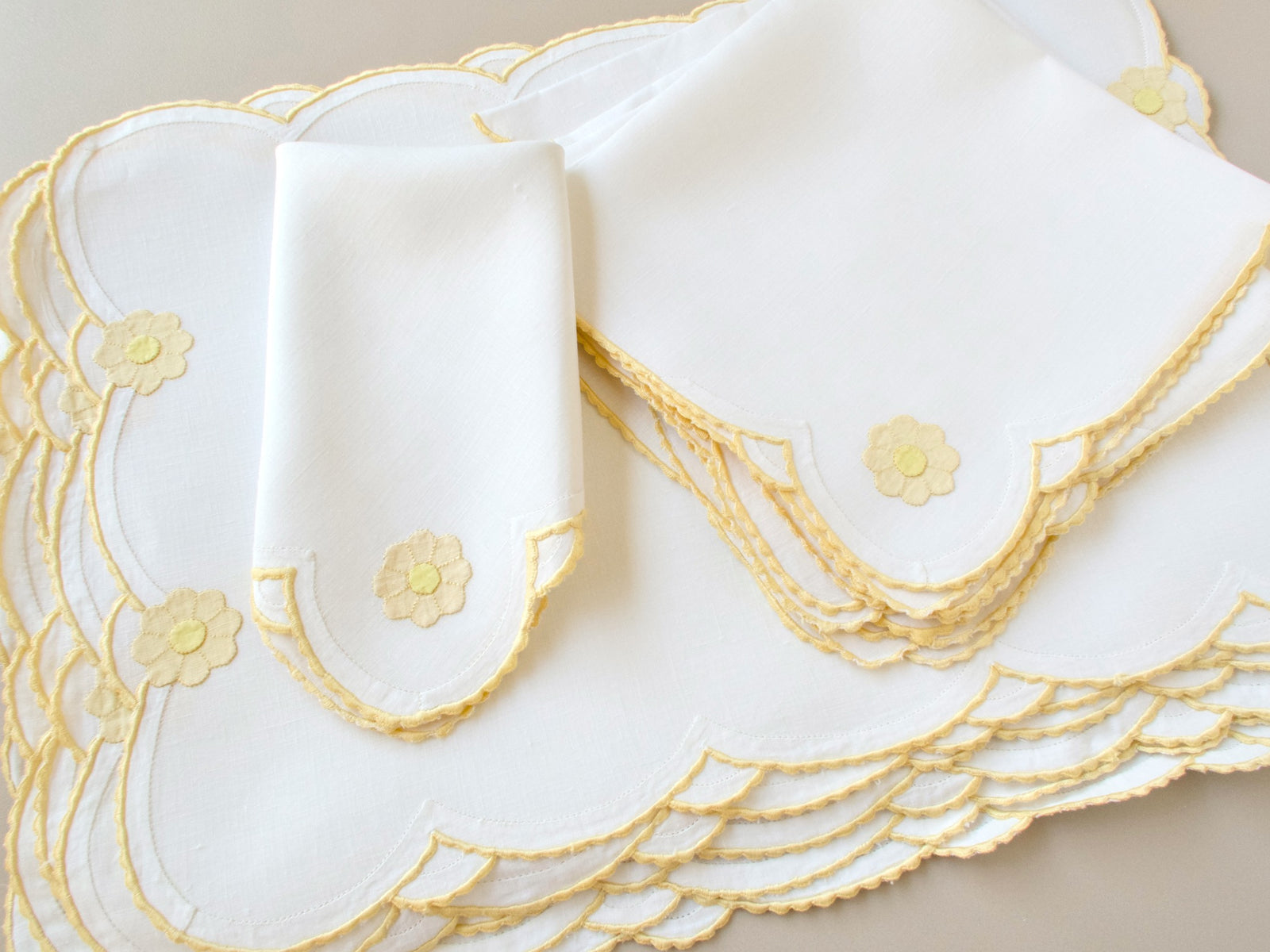 Vintage Madeira daisy placemats and napkins stacked showing full set, creamy Irish linen with yellow daisy appliqué and scalloped border detail​​​​​​​​​​​​​​​​