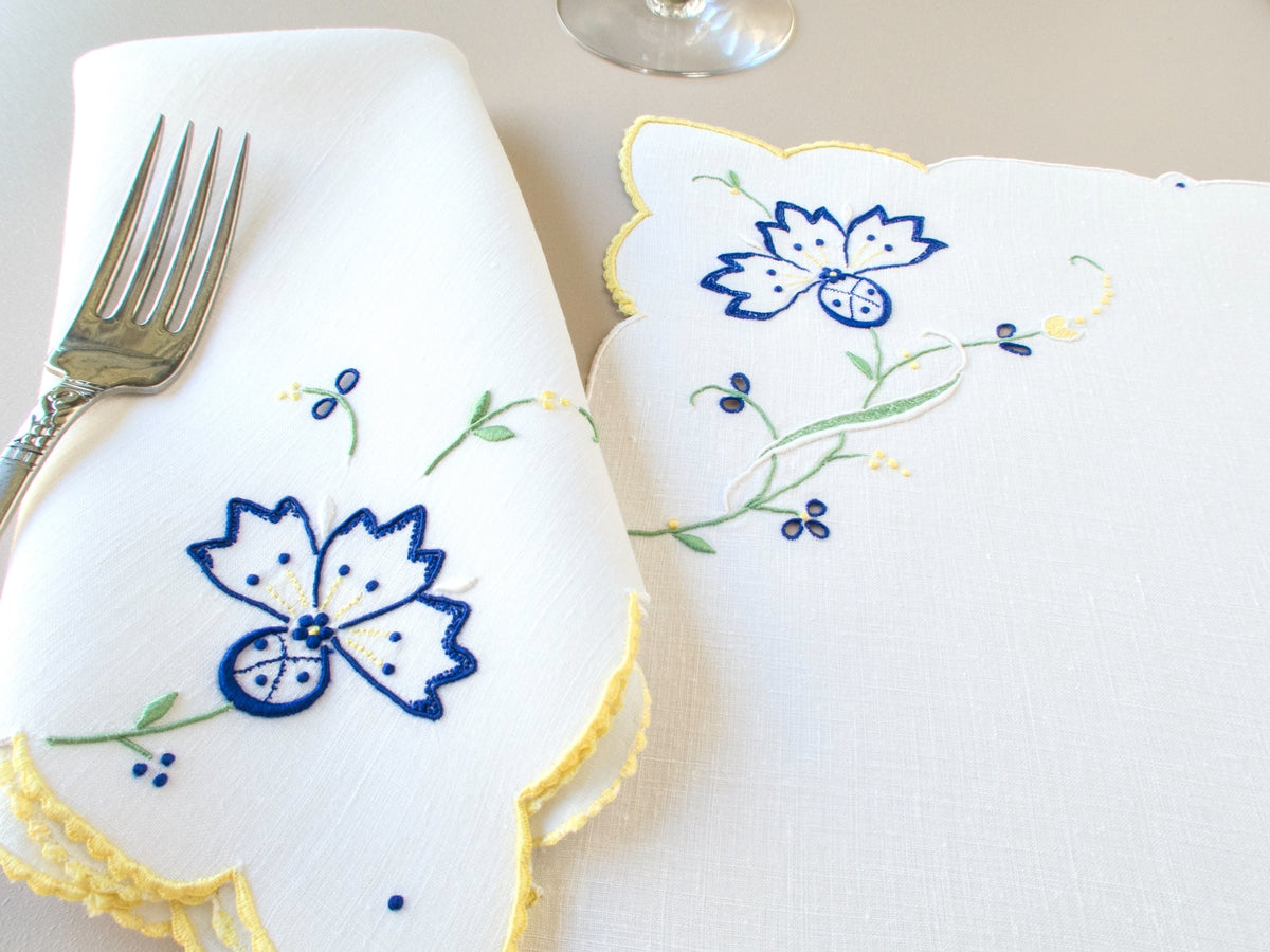 Vintage Madeira placemat set, white Irish linen with yellow scalloped border, blue cornflower embroidery, fork and napkin styled on table