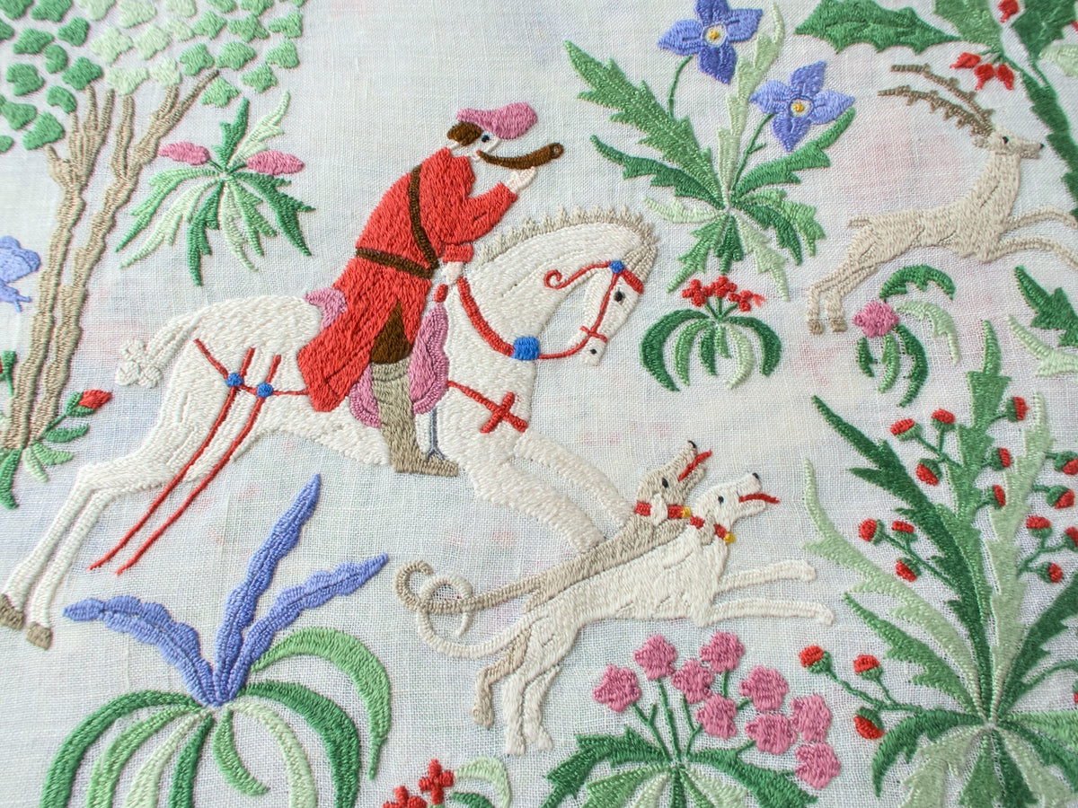 Embroidered scene with a hunter on horseback surrounded by flowers and plants, vintage Rapisardi Italian handwork on linen.