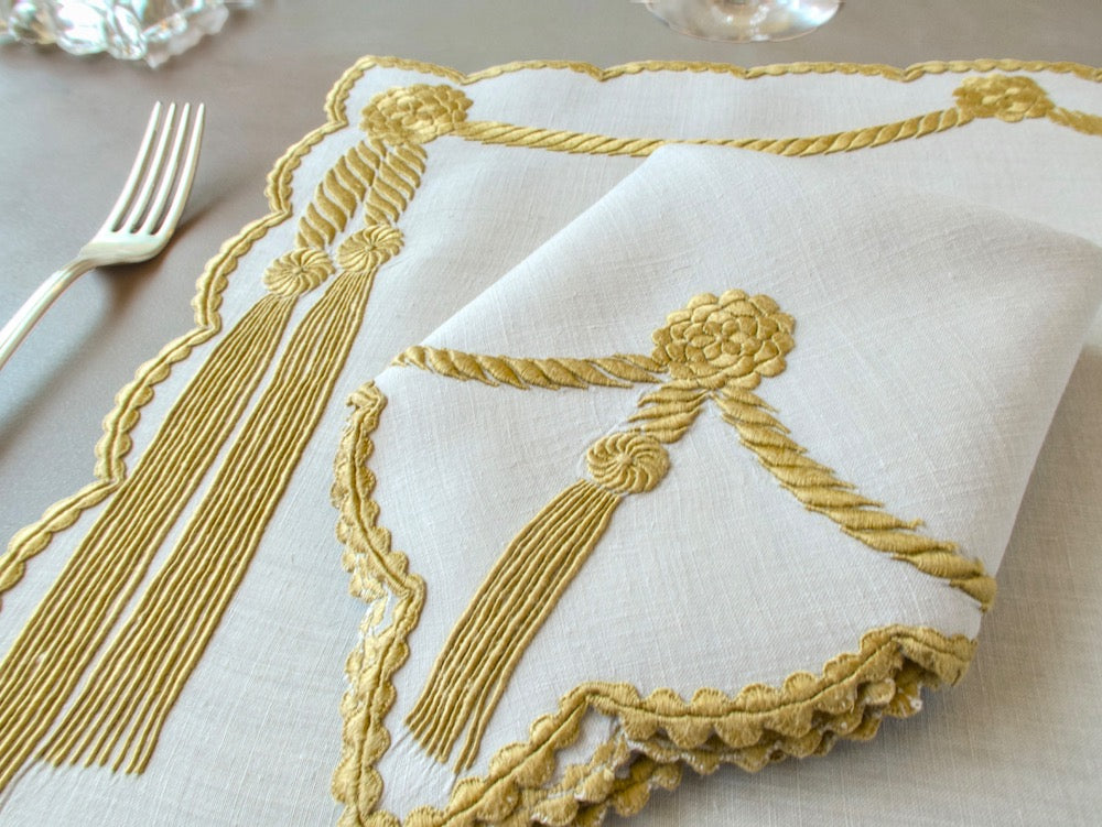 Vintage Marghab Cord &amp; Tassel placemat and napkin in antique bullion gold on ecru linen, shown with silver fork on warm taupe surface