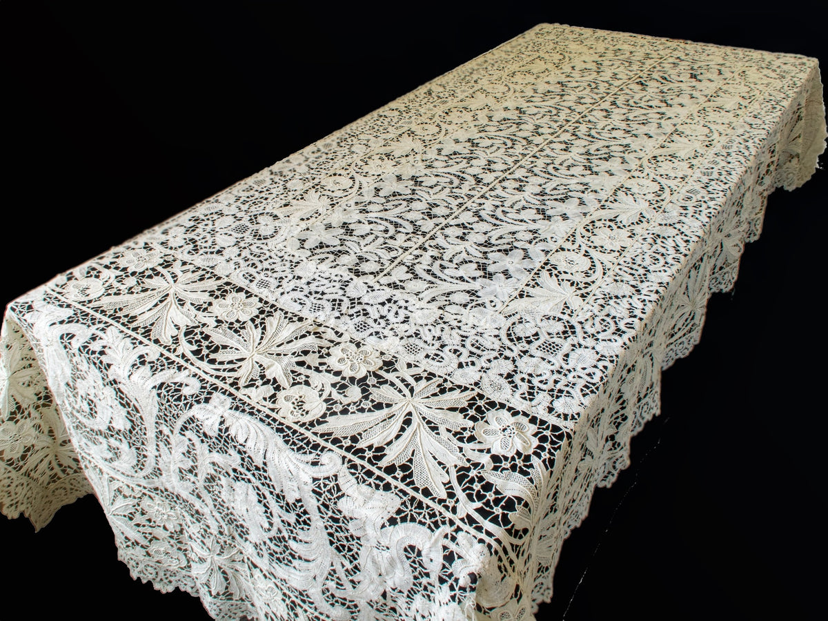Full view of an antique French mixed lace tablecloth, 55 x 102 inches, draped over a table