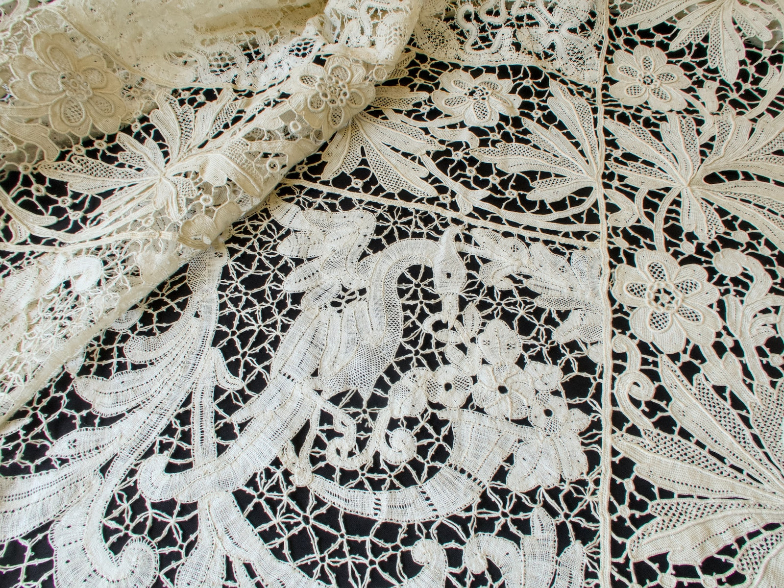 Close view of a graceful crane in handmade bobbin lace with flowers and a net ground