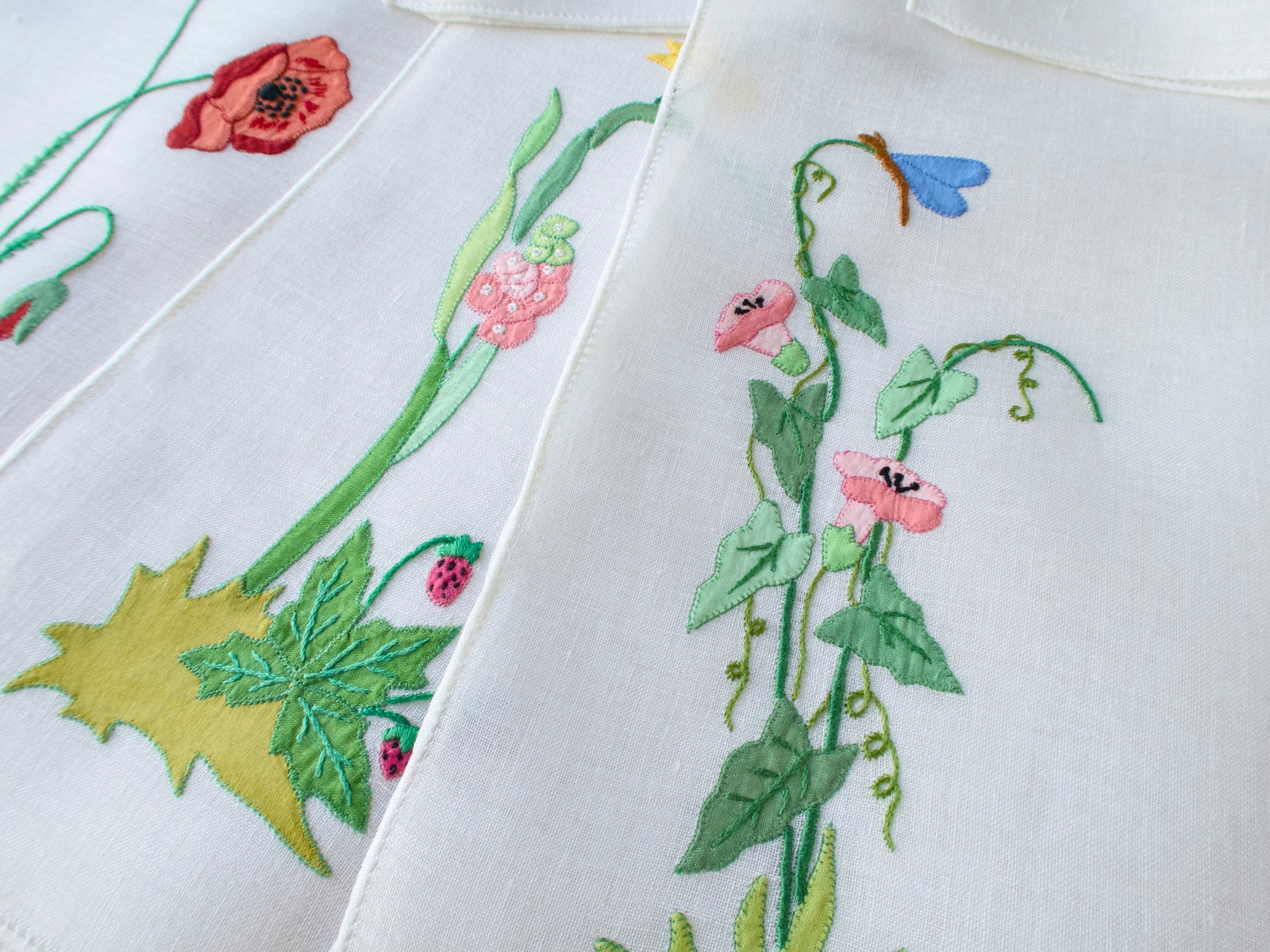 Vintage Italian linen placemat showing hand embroidered blue and white flowers with butterfly detail