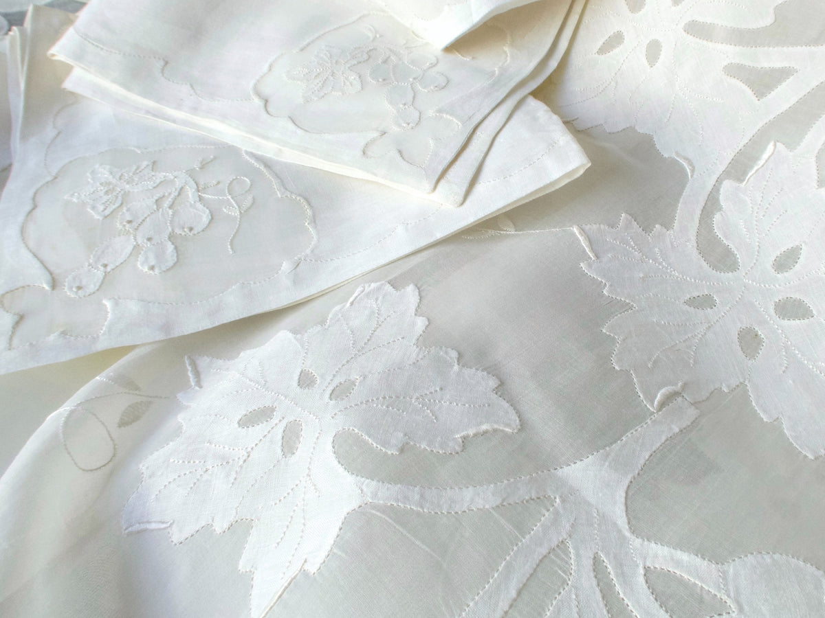 Detail of white embroidered grape leaves beside the matching napkins.