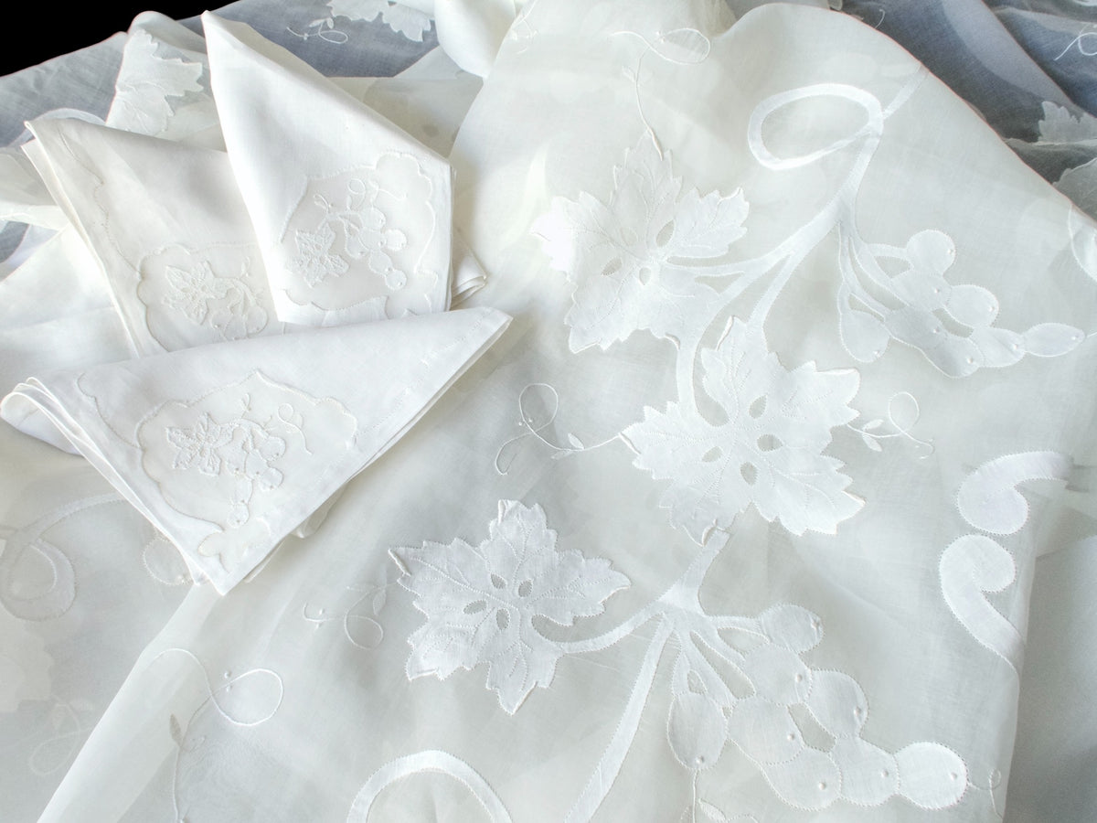 Folded grape and leaf napkins arranged on the embroidered organdy tablecloth.