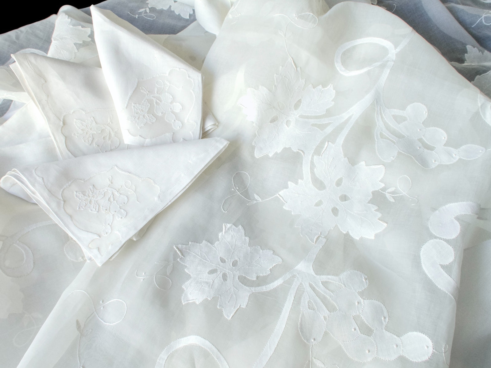 Folded grape and leaf napkins arranged on the embroidered organdy tablecloth.