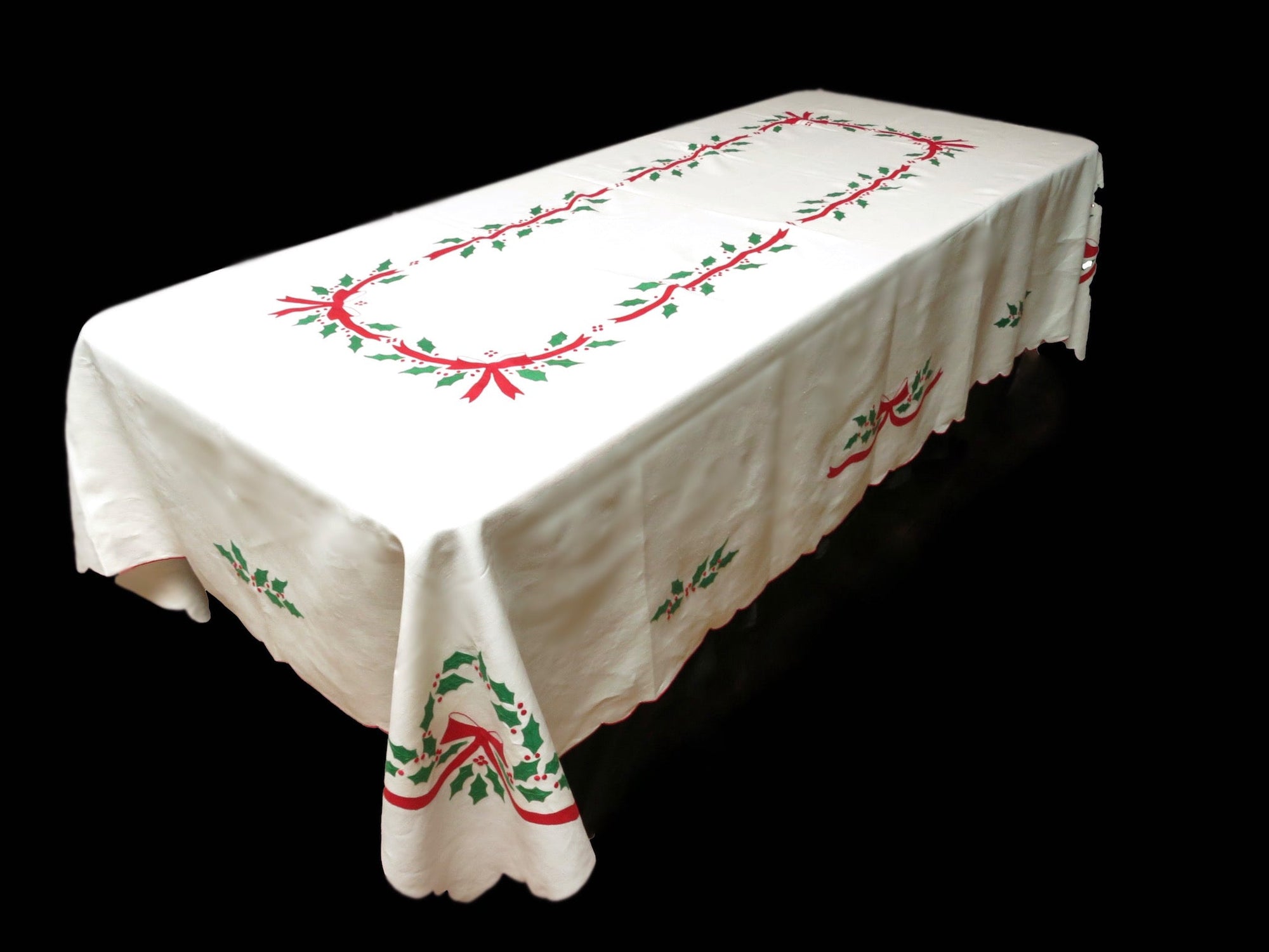 Full view of white linen tablecloth with red bow and green holly embroidery