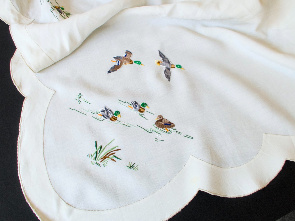 Close-up of colorful hand embroidered mallards and reeds on vintage Madeira tablecloth