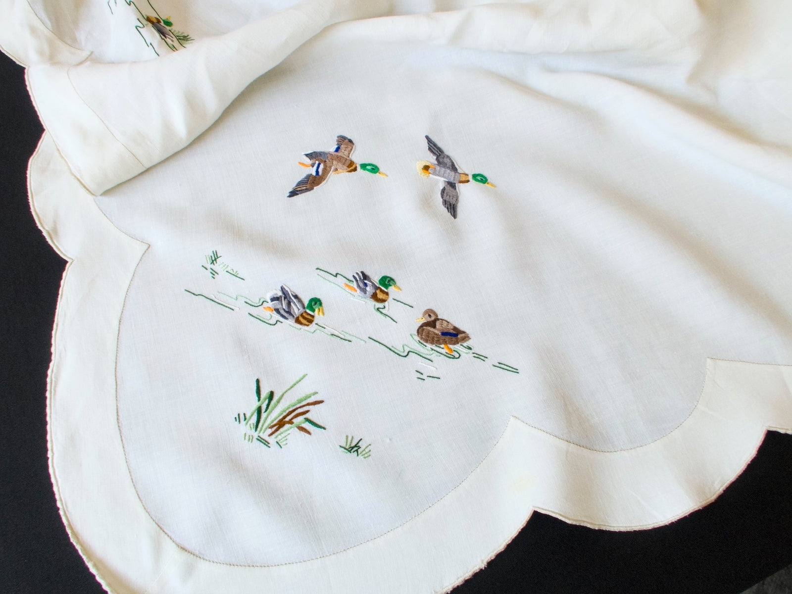 Close-up of colorful hand embroidered mallards and reeds on vintage Madeira tablecloth