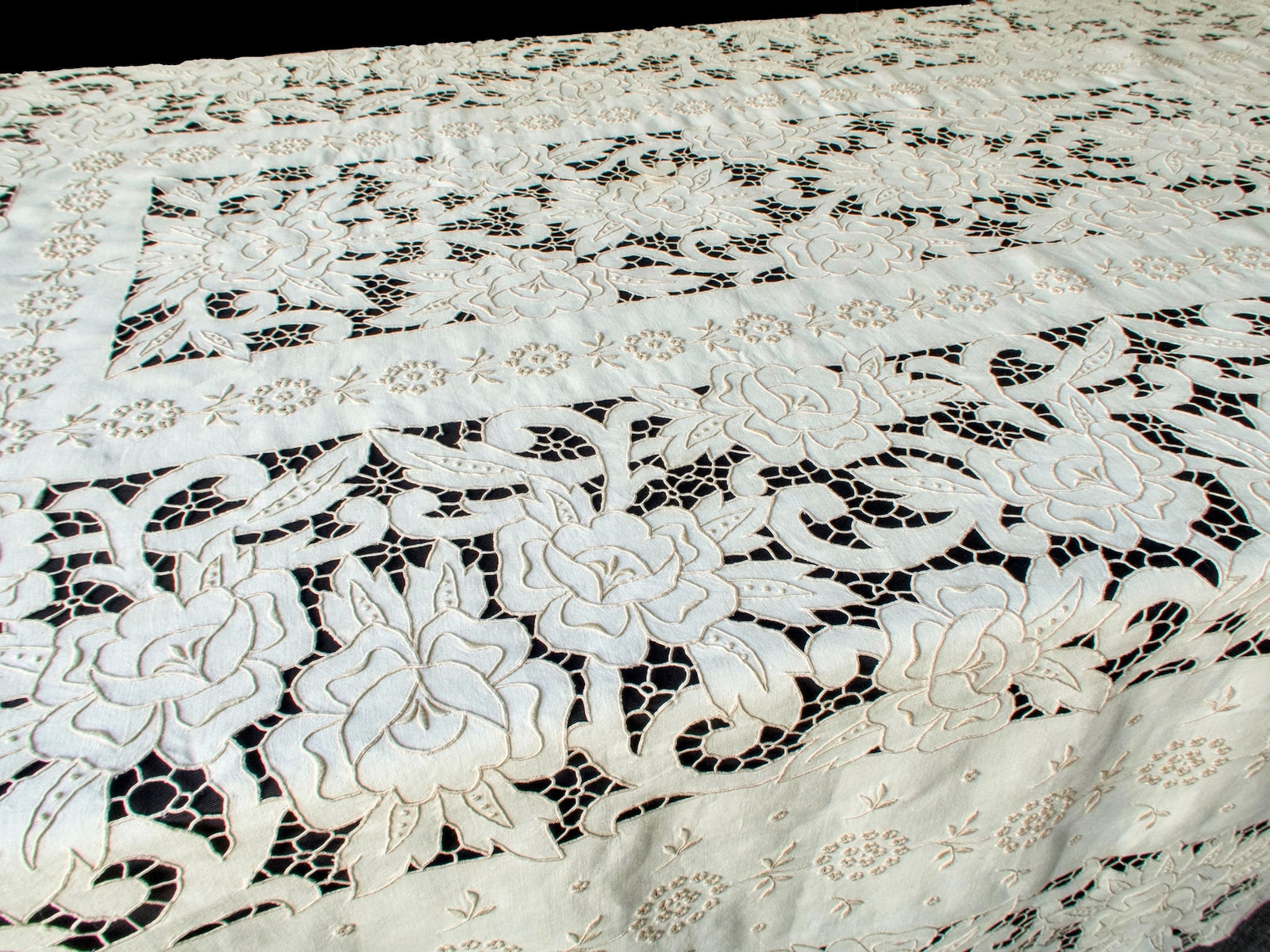 Raised embroidery and cutwork details of Madeira tablecloth seen in angled light, highlighting depth and hand-stitching.