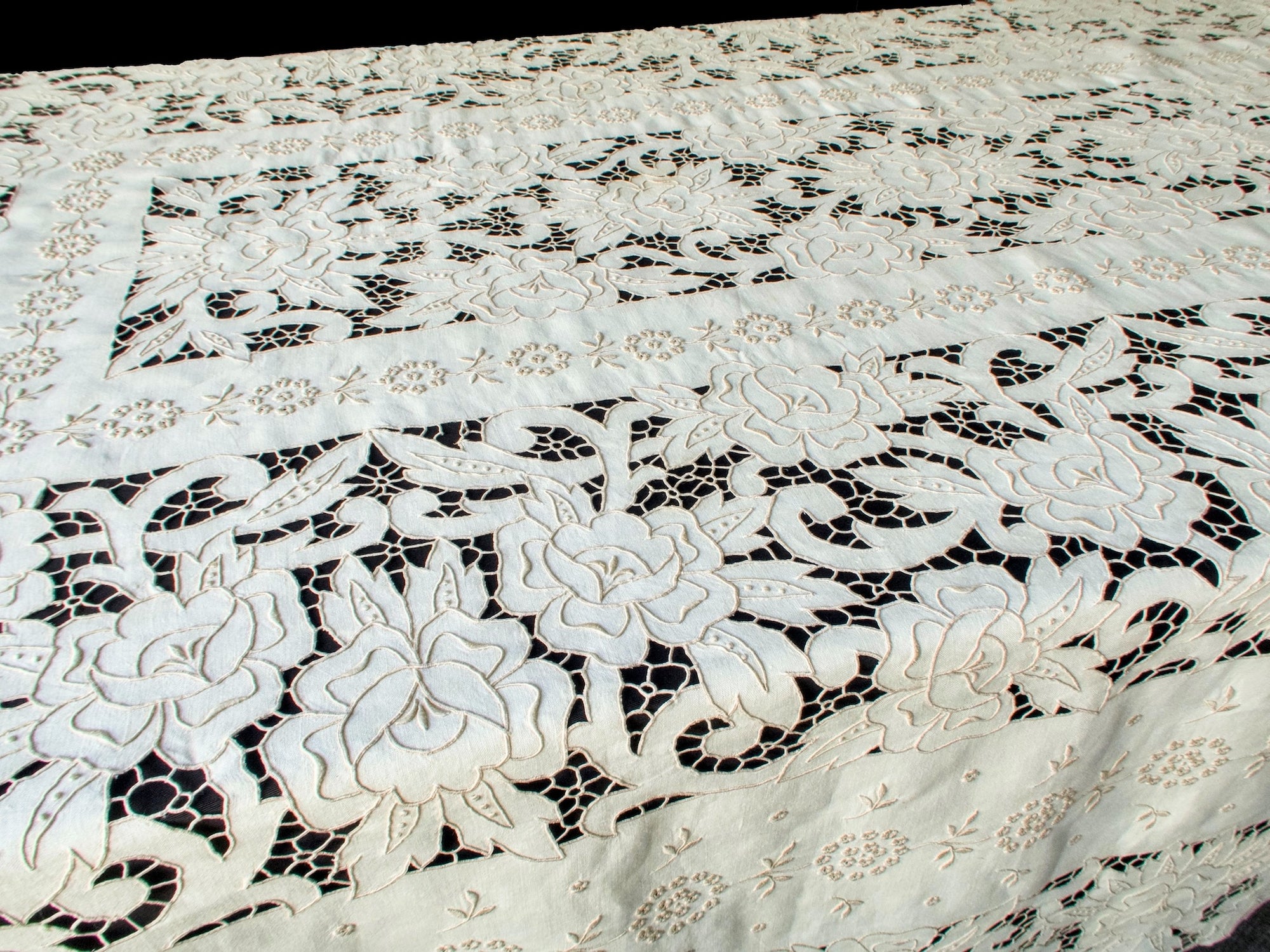 Raised embroidery and cutwork details of Madeira tablecloth seen in angled light, highlighting depth and hand-stitching.