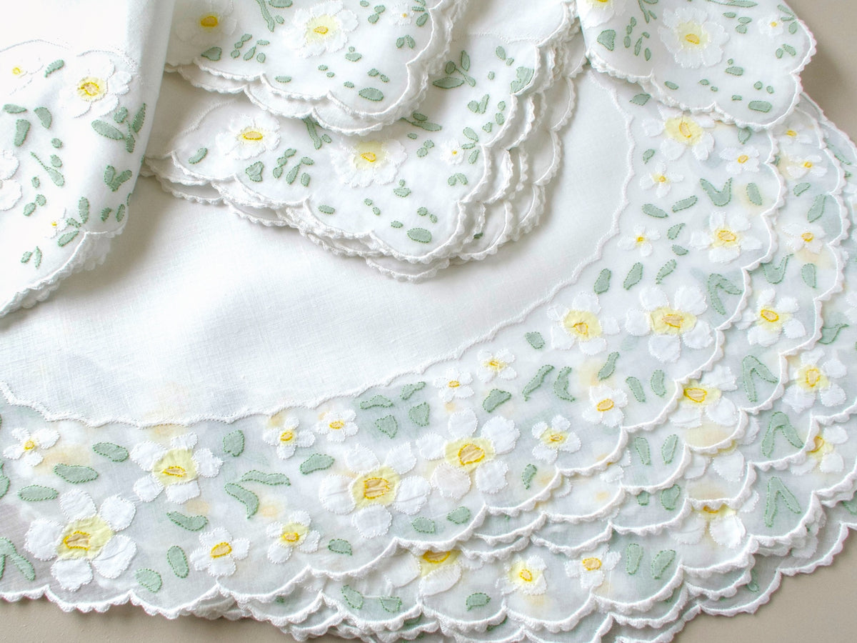 Stack of eight vintage Madeira napkins with white appliquéd daisies and scalloped borders showing full set
