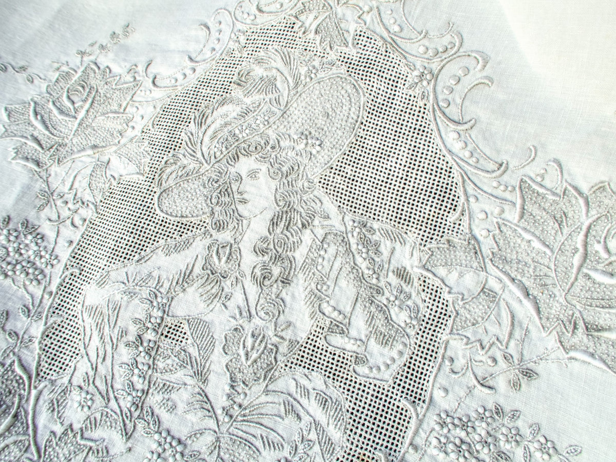 Close-up of Appenzell embroidery showing lady in period dress with dense stitched detail and lace-style background