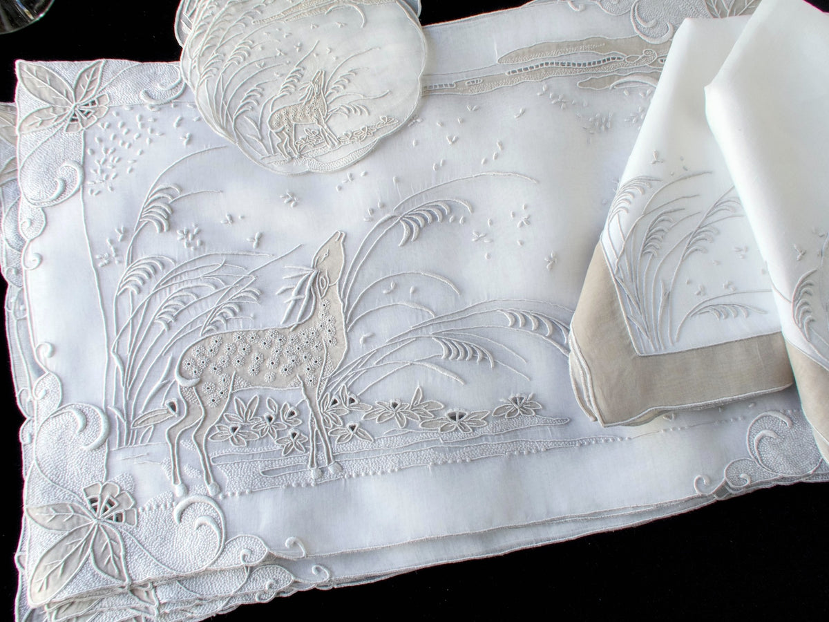 Stacked vintage Marghab “Deer” organdy placemats showing full embroidered landscape scene with deer, grasses, and crescent moon in light gray.