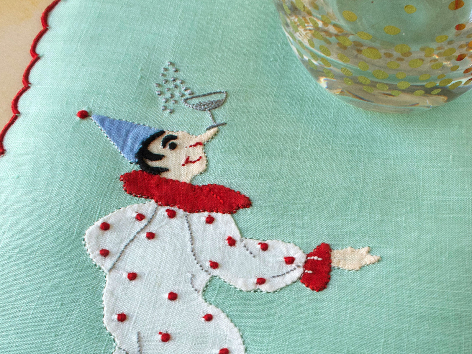 Clown balances a glass of champagne on his nose, embroidered vintage Madeira cocktail napkins
