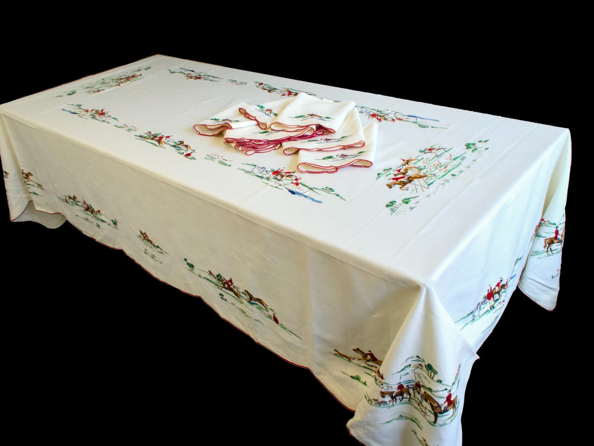 Full 68 x 112 inch vintage Madeira tablecloth on a table with fox hunt scenes embroidered around the border and napkins in the center
