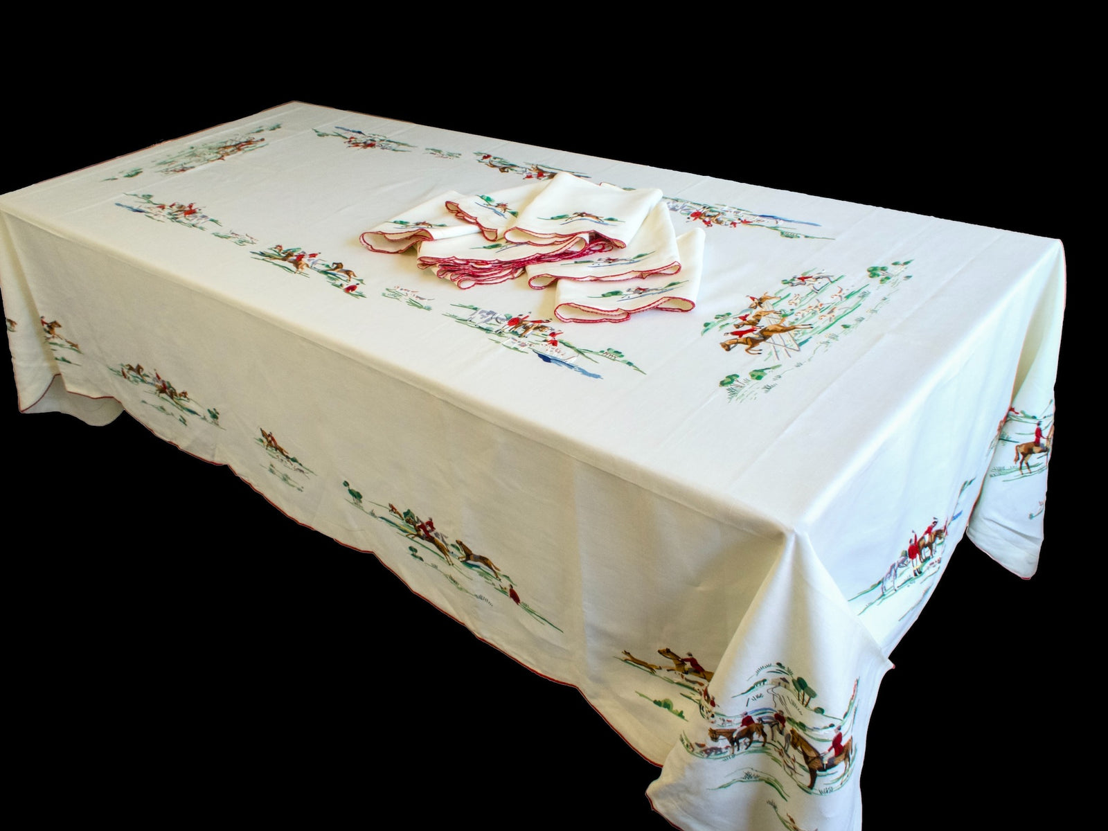 Full 68 x 112 inch vintage Madeira tablecloth on a table with fox hunt scenes embroidered around the border and napkins in the center