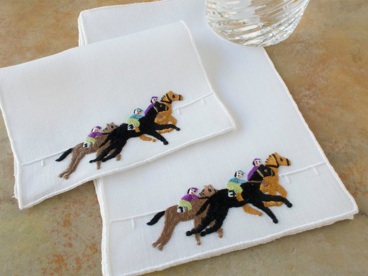 Two vintage Madeira horse race cocktail napkins with a cocktail glass in the background