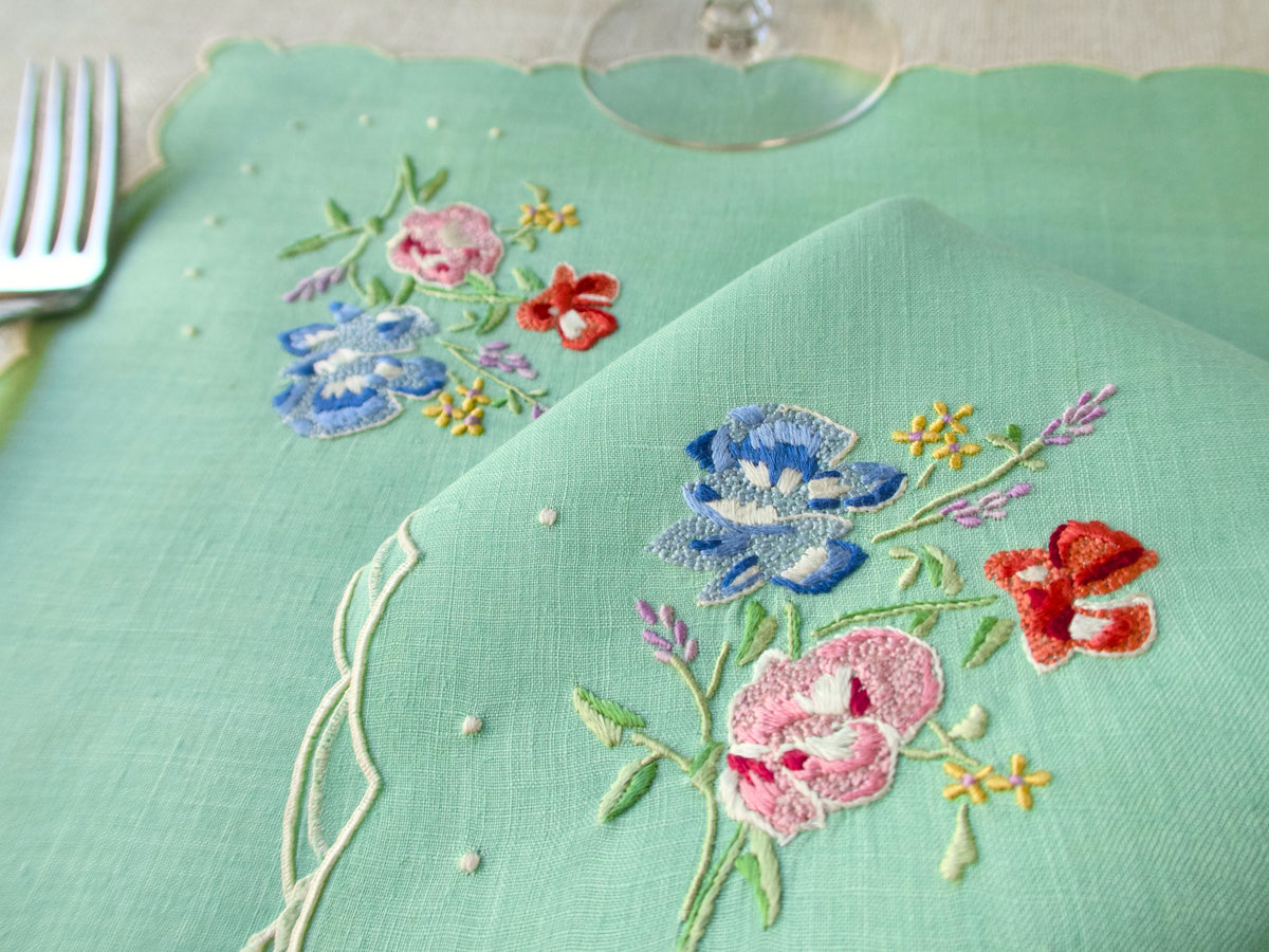 Close up of embroidered flowers on soft green Irish linen vintage Madeira placemat set.