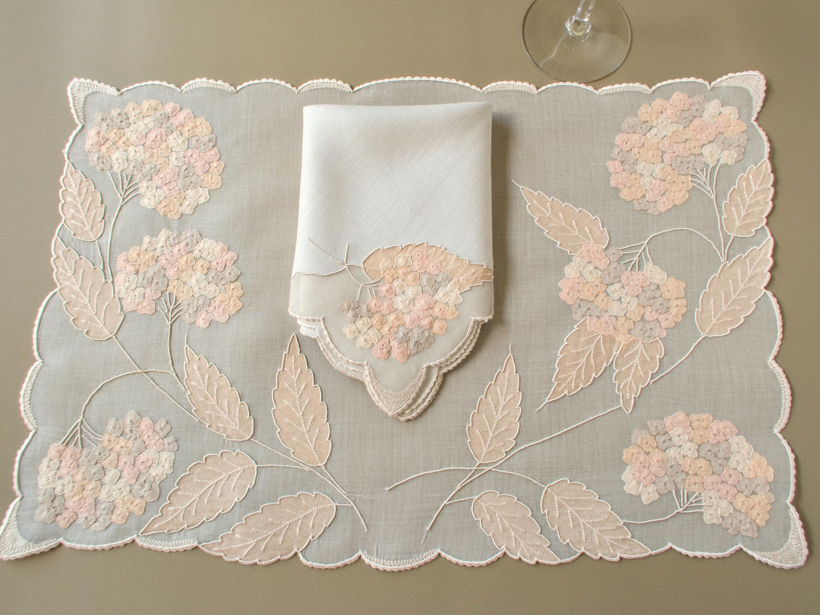 Vintage Marghab “Hydrangea” placemat and napkin set, hand embroidered in Madeira on fine organdy and linen, featuring intricate hydrangea blossoms in soft shades of cream and beige.